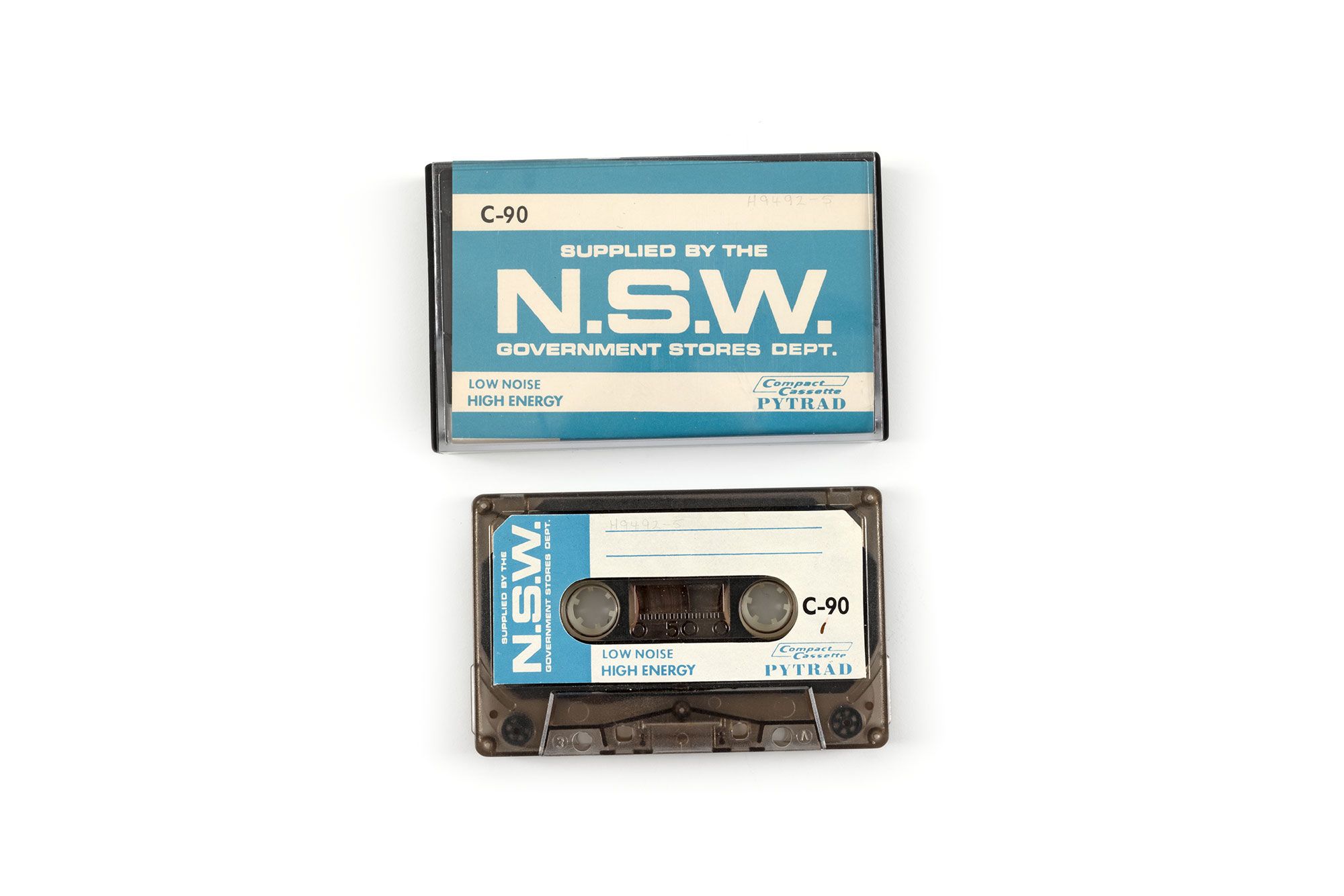 Plastic audio cassette tape in a plastic case with a blue and white cardboard insert. Text on the insert reads ‘C-90, low noise, high energy, "Pyrtrad", "Supplied by the N.S.W Government Stores Dept."’.