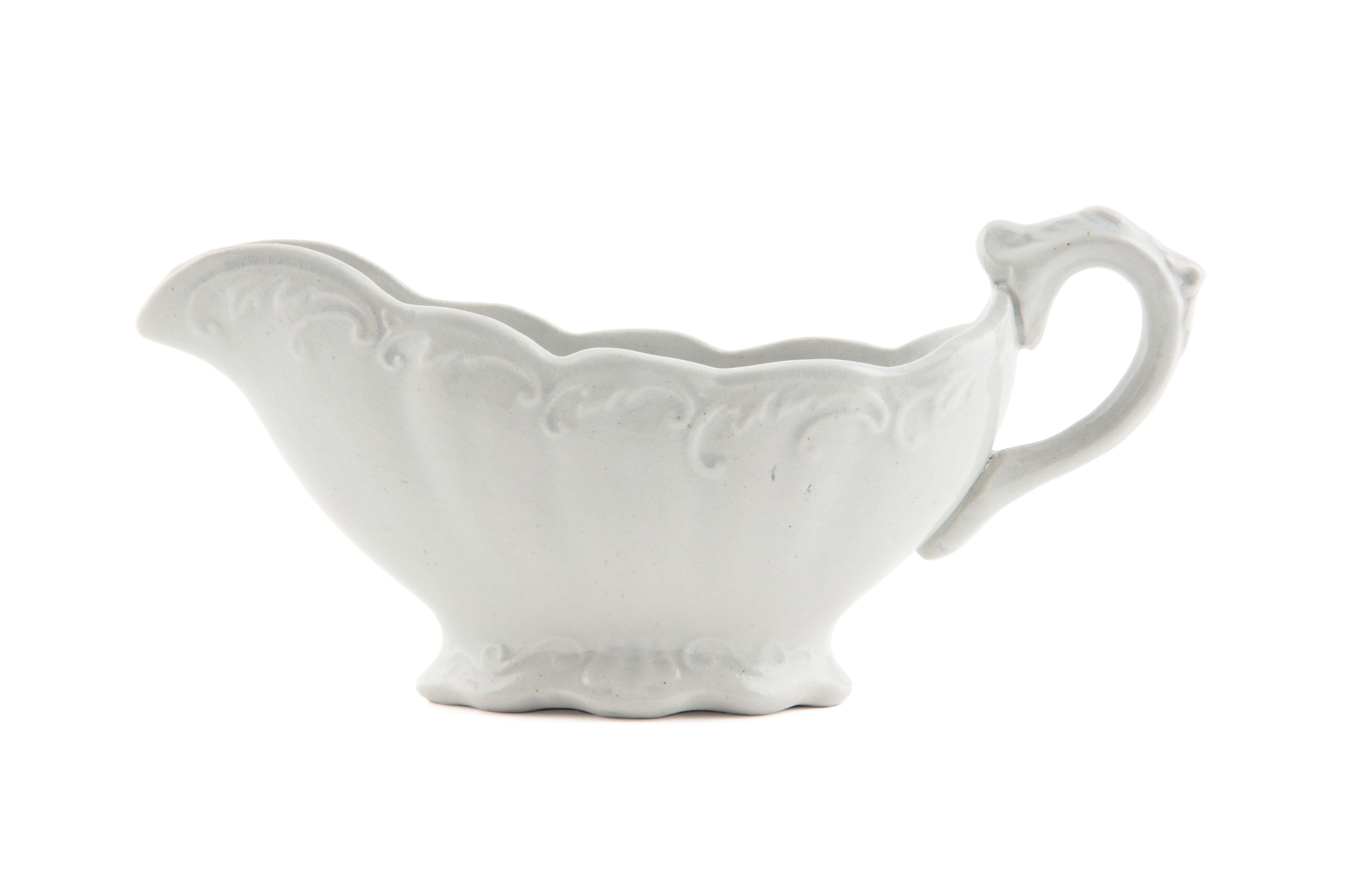 White ceramic jug, low and wide, with scalloped edging around the rim and base along with a raised swirling patterning, photographed against a white background.