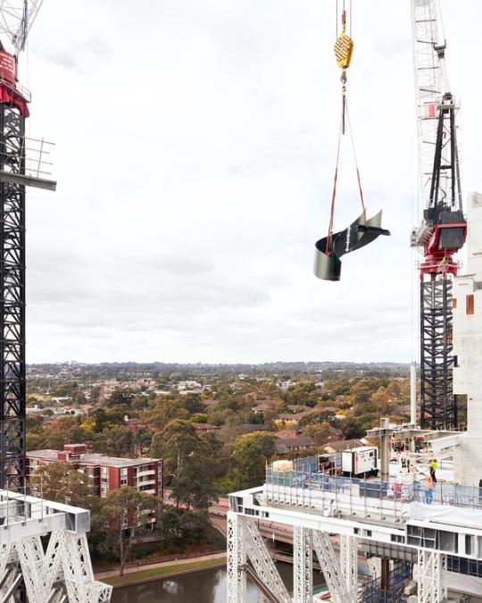 Green staircase getting lifted down by crane.