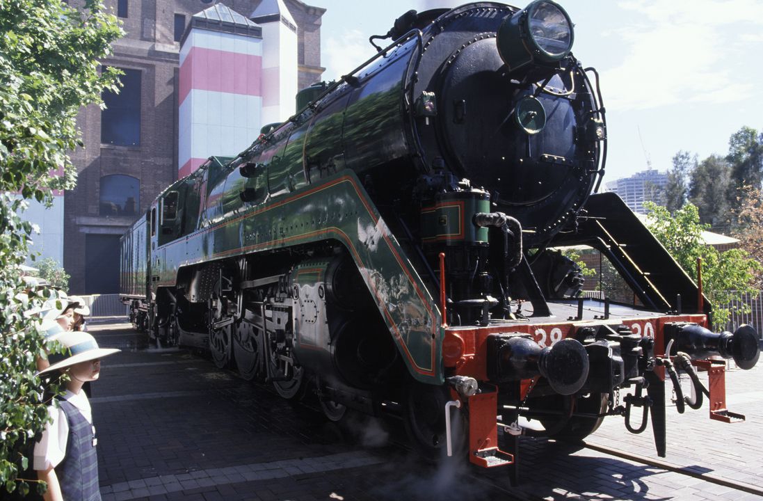Old black steel locomotive on a rail line pulling several carriages