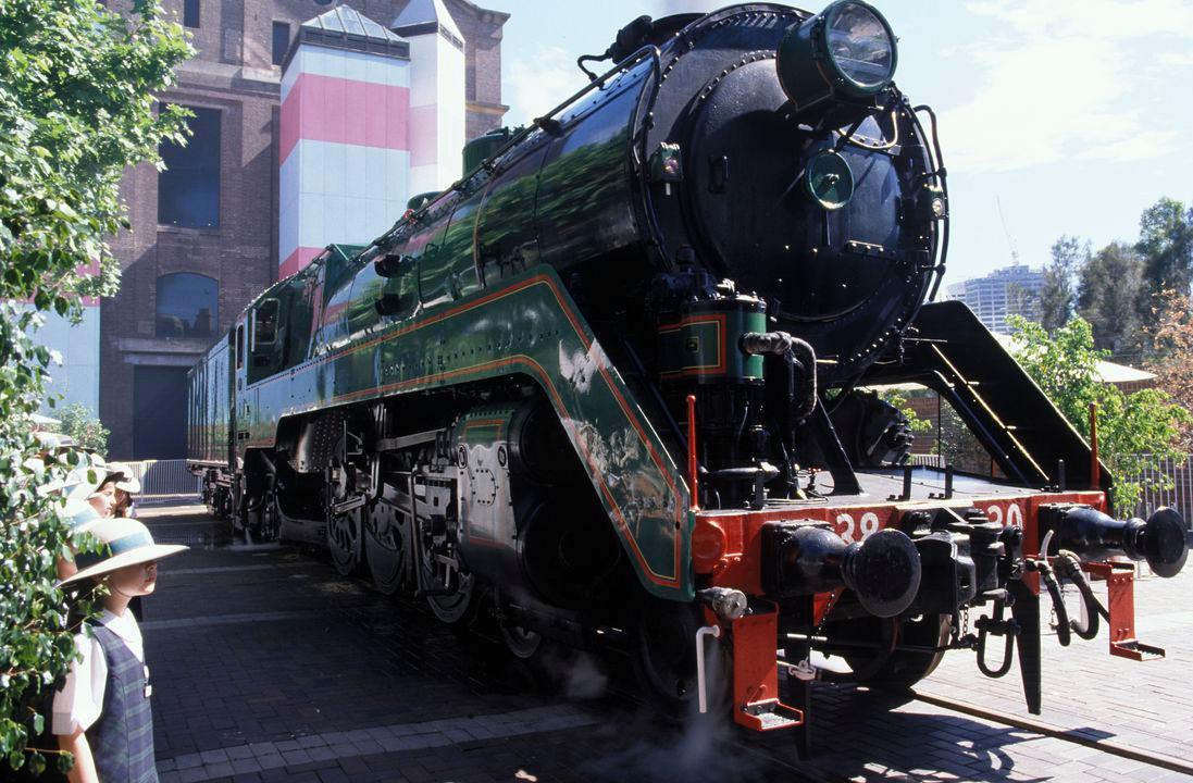Old black steel locomotive on a rail line pulling several carriages