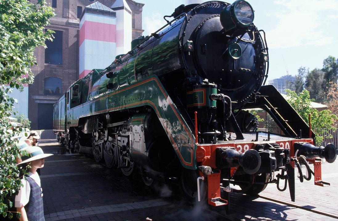 Old black steel locomotive on a rail line pulling several carriages