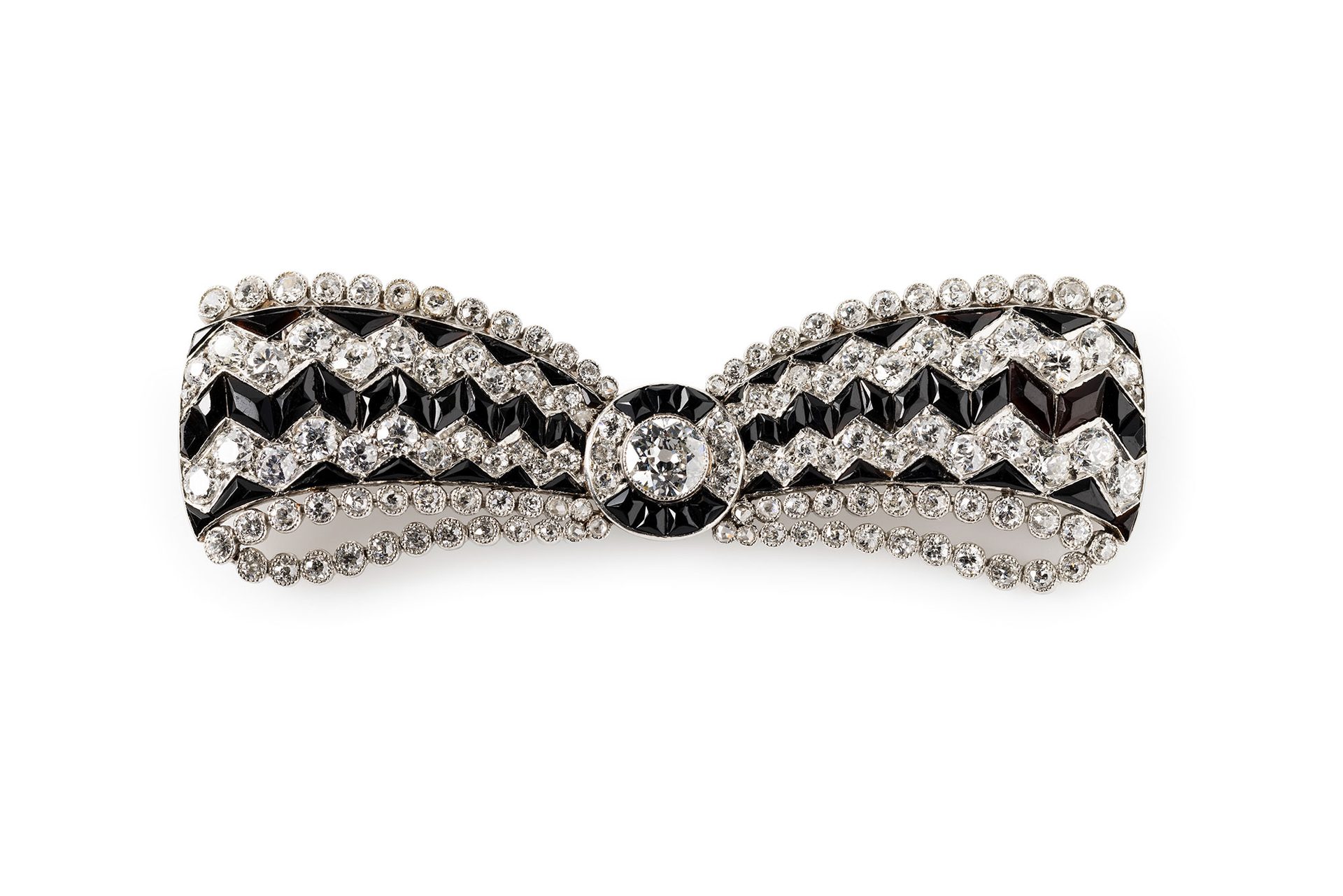 A brooch made out of white metal set with clear and black stones in a jewellery box.
