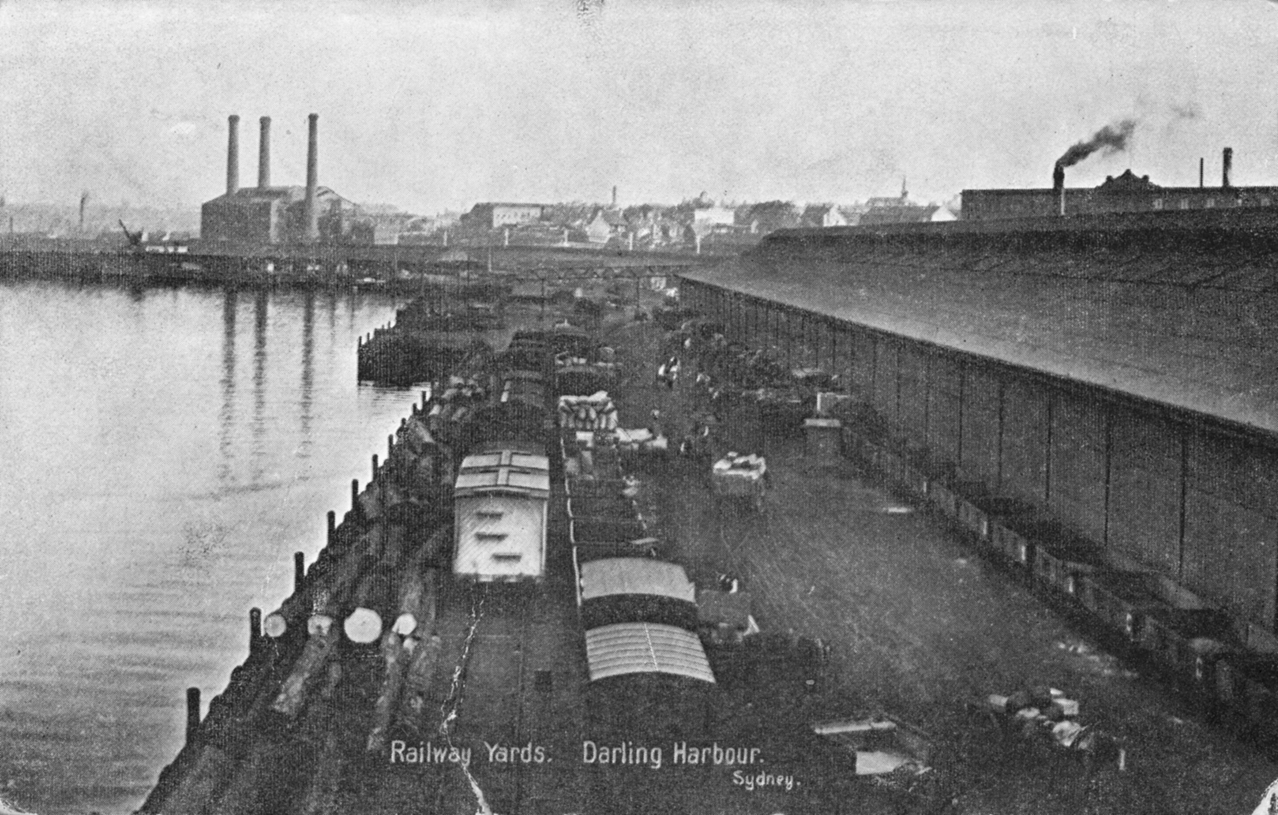 Trams lined up inbetween the harbour water and a large warehouse