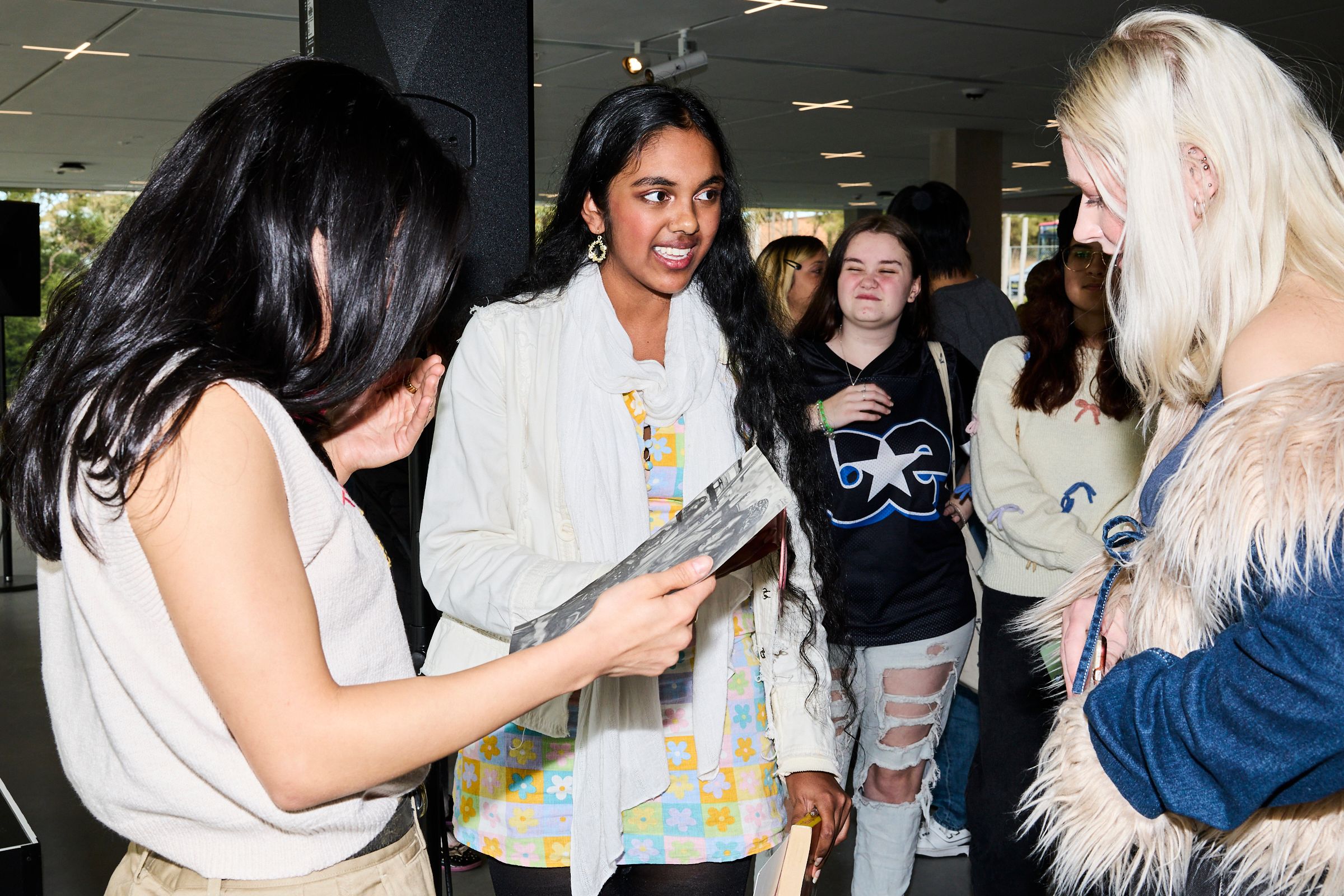Ayesha Madon and two guests in conversation, looking down at a handmade gift.