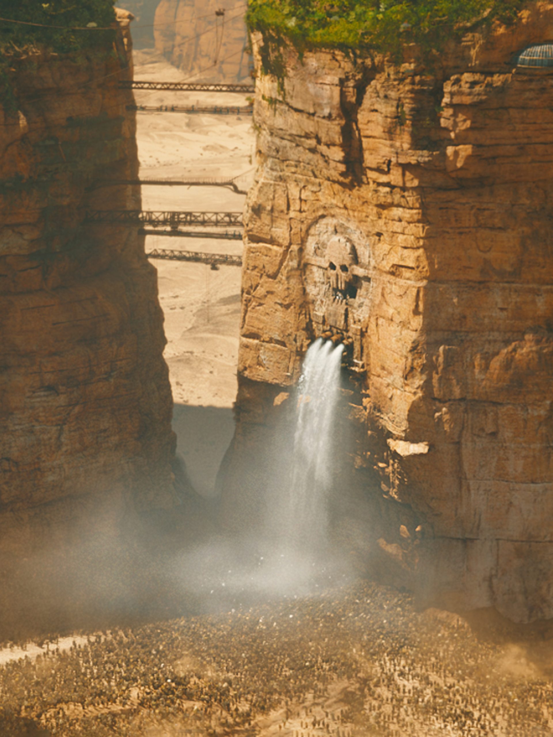 Waterfall falling below skull carved into cliffside.