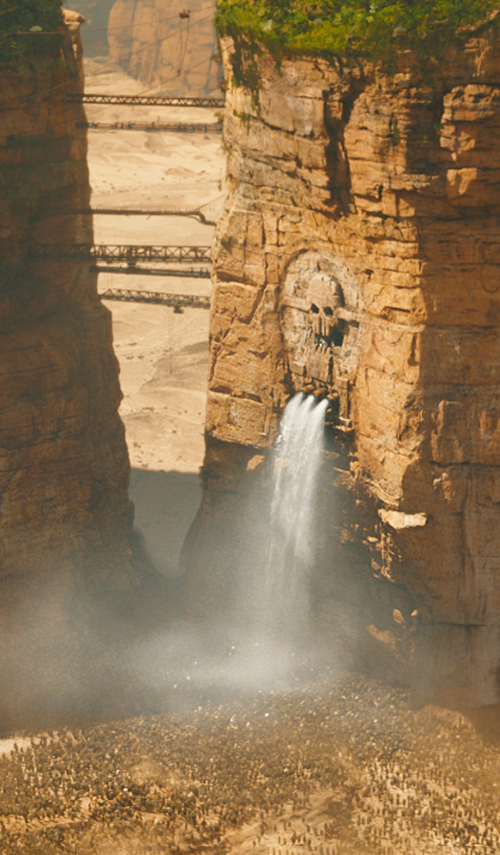 Waterfall falling below skull carved into cliffside.