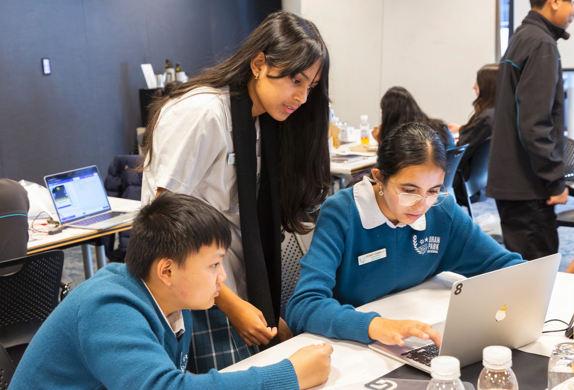 Three students working around a laptop.