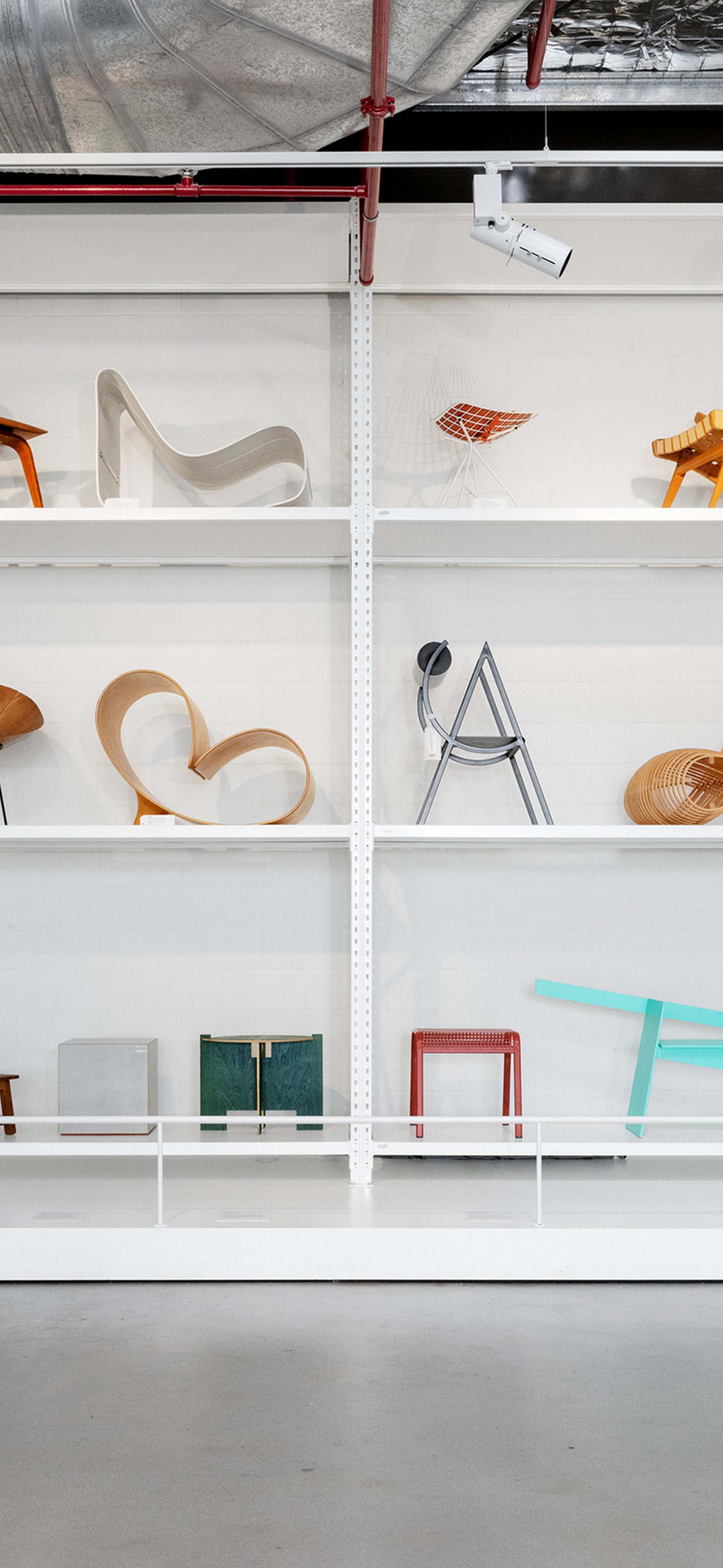Three shelves filled with colourful chairs and stools.