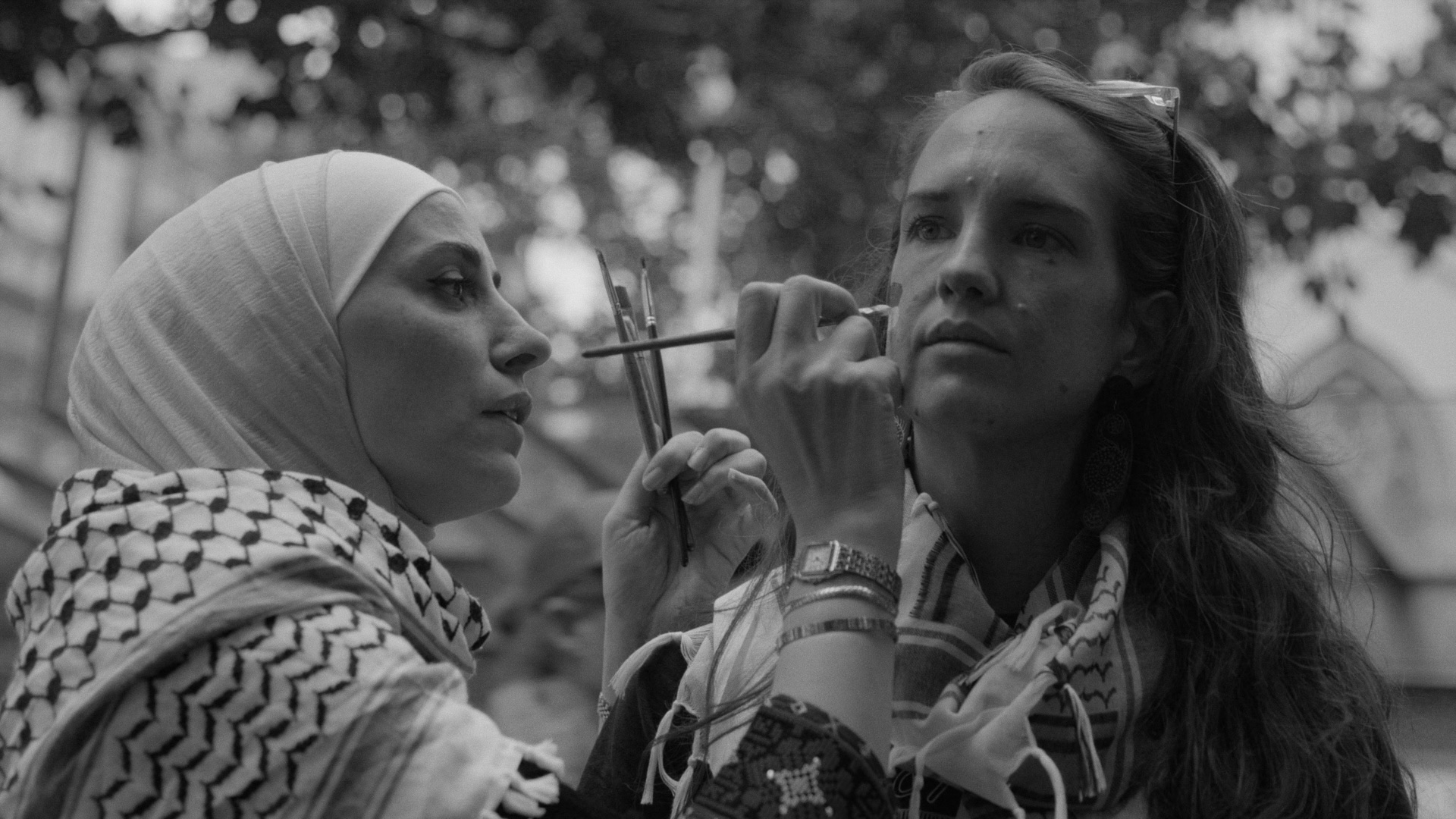 A Palestinian woman paints the face of a Gumbaynggirr woman.