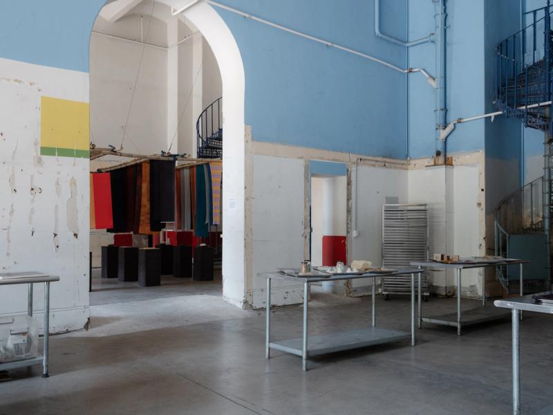 Exhibition space with metal tables and hanging fabrics