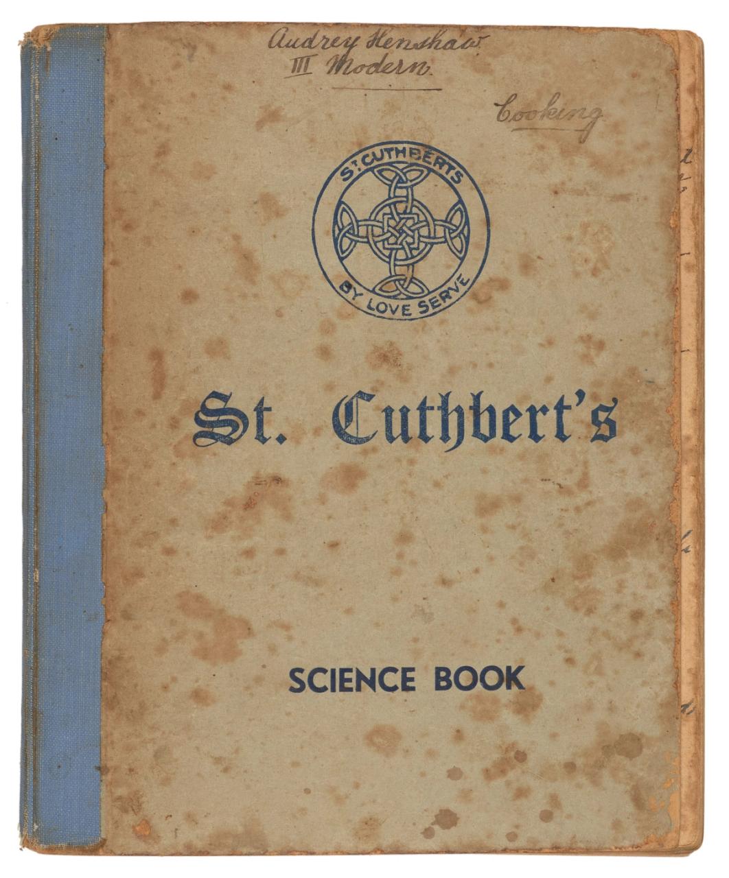 Yellowing cover of a blue-spined ‘St Cuthbert’s Science Book’ with ‘Audrey Henshaw’ and ‘Cooking’ handwritten at the top, and with loose pages collected inside.
