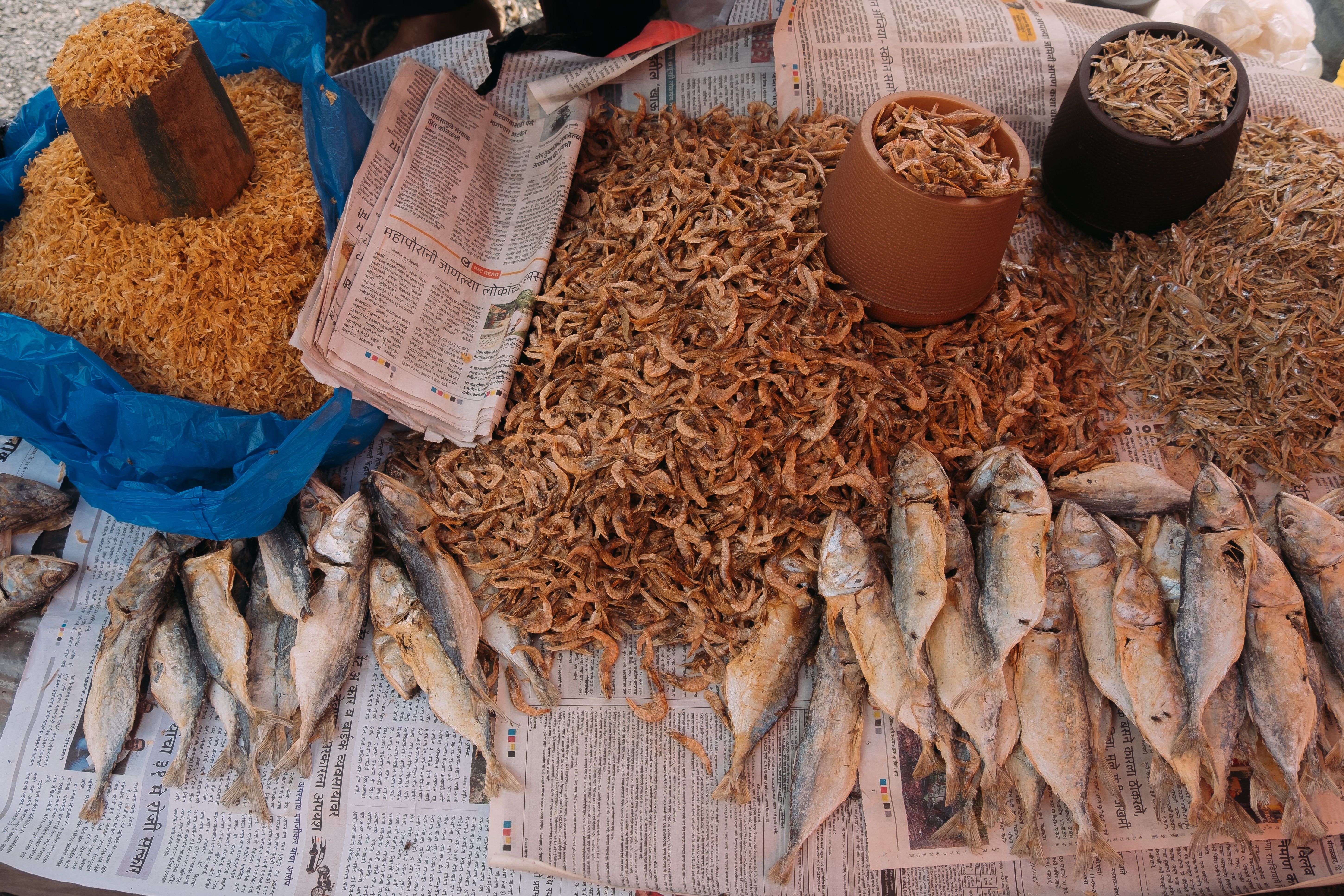 Tiny, small and medium dried fish on newspapers.