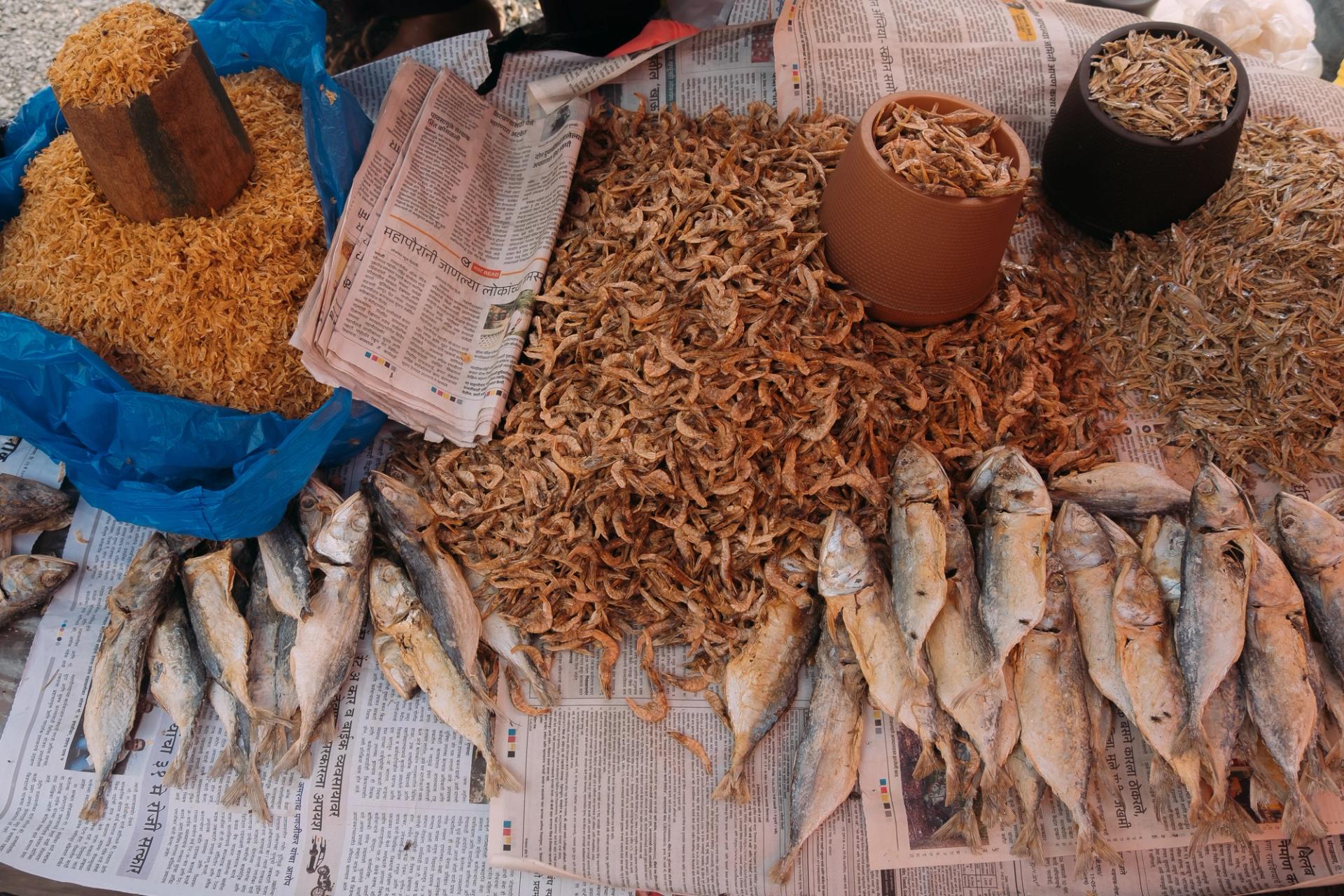 Tiny, small and medium dried fish on newspapers.