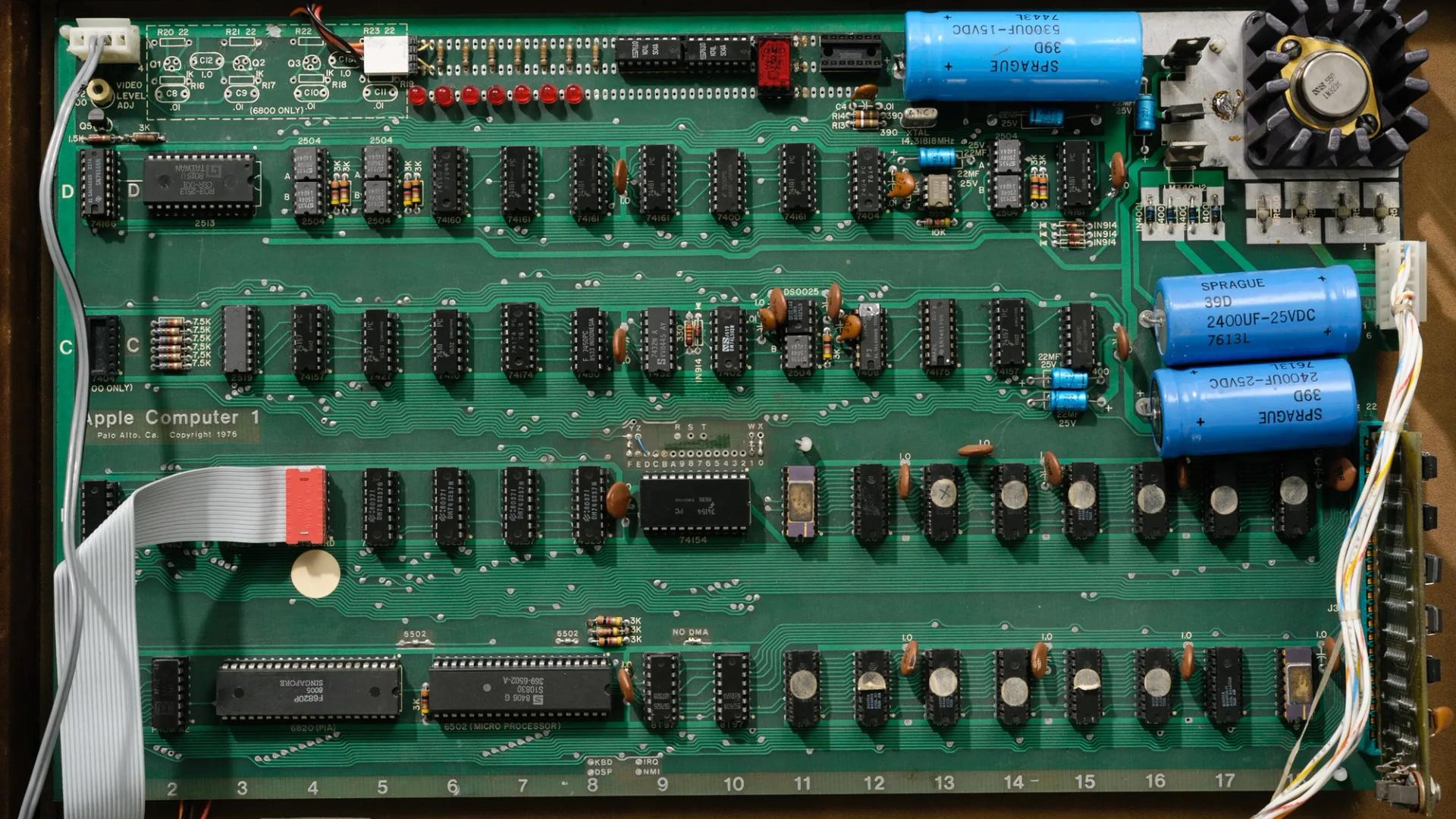 An open briefcase revealing the Apple 1 printed circuit board and components attached to the underside of the briefcase lid.