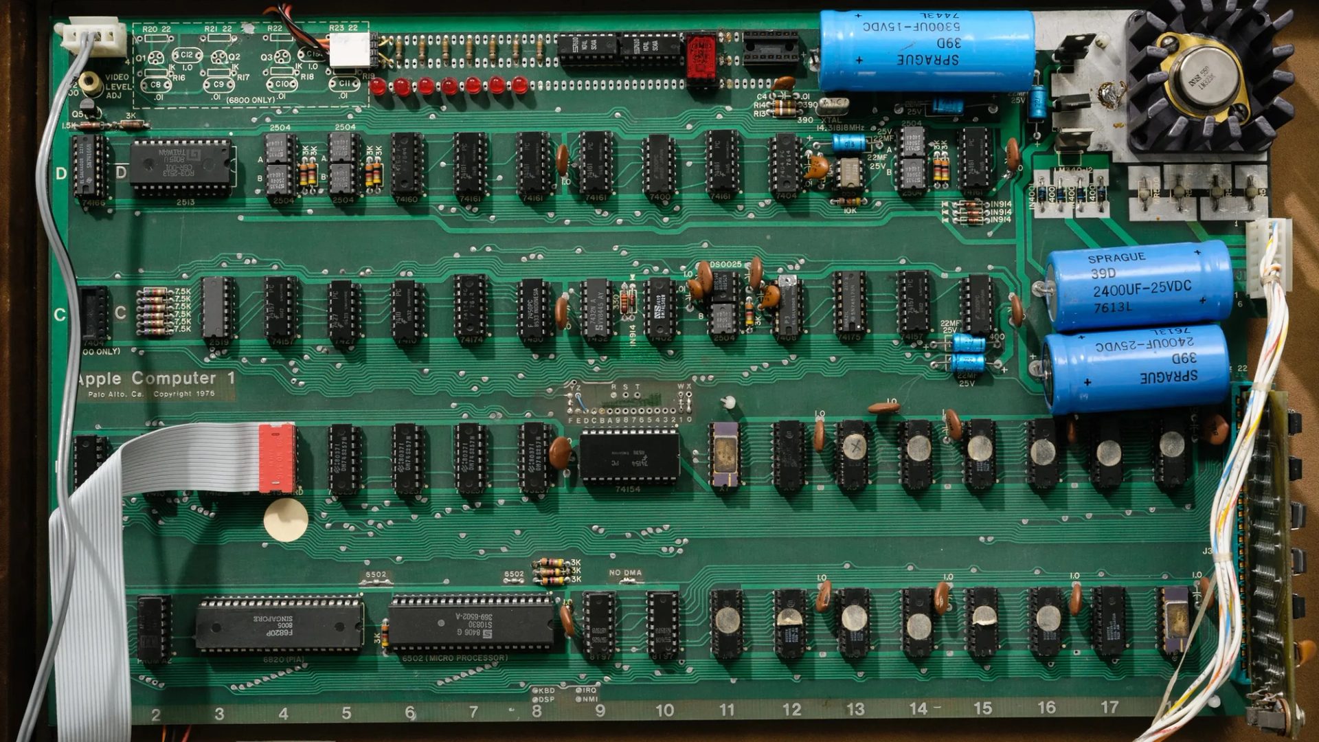An open briefcase revealing the Apple 1 printed circuit board and components attached to the underside of the briefcase lid.