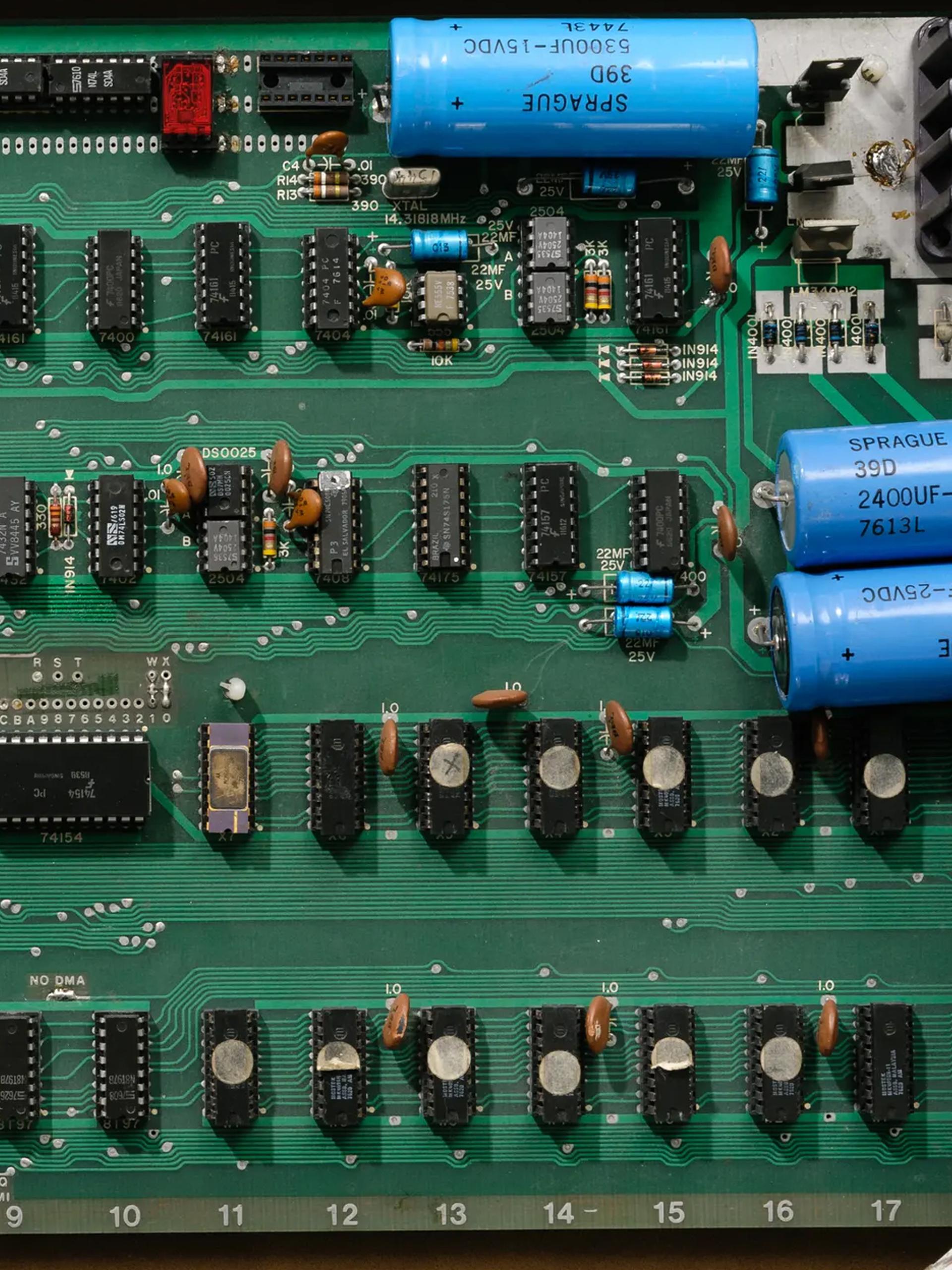 An open briefcase revealing the Apple 1 printed circuit board and components attached to the underside of the briefcase lid.