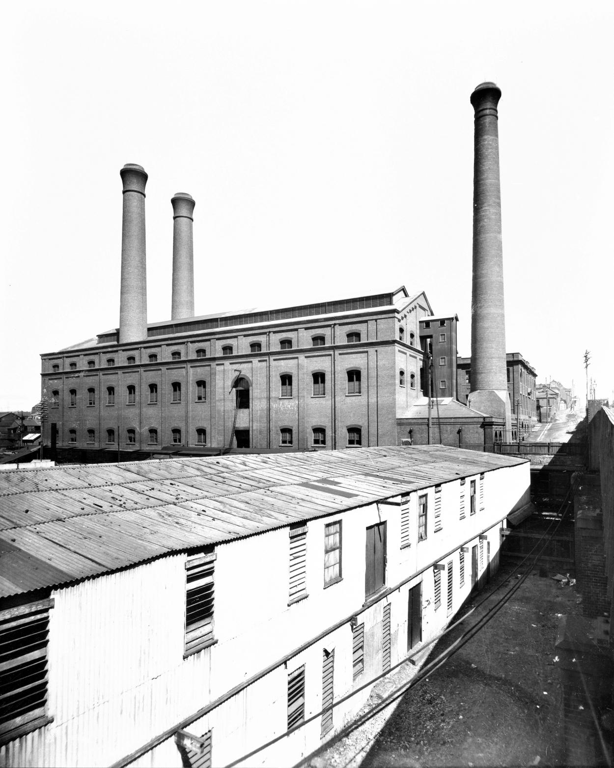 Black and white photograph of large brick Boiler Hall with three chimenys
