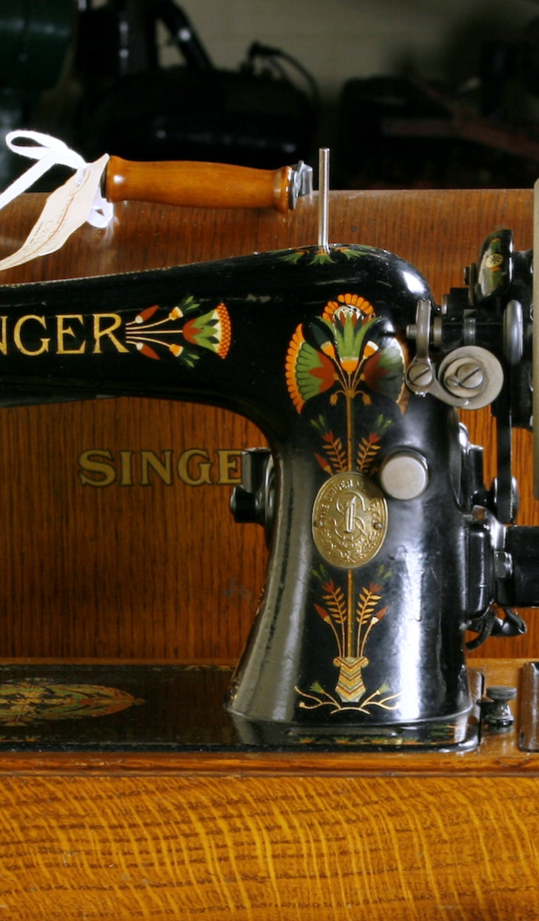 A black sewing machine with yellow, red and green flowers in a wooden box.