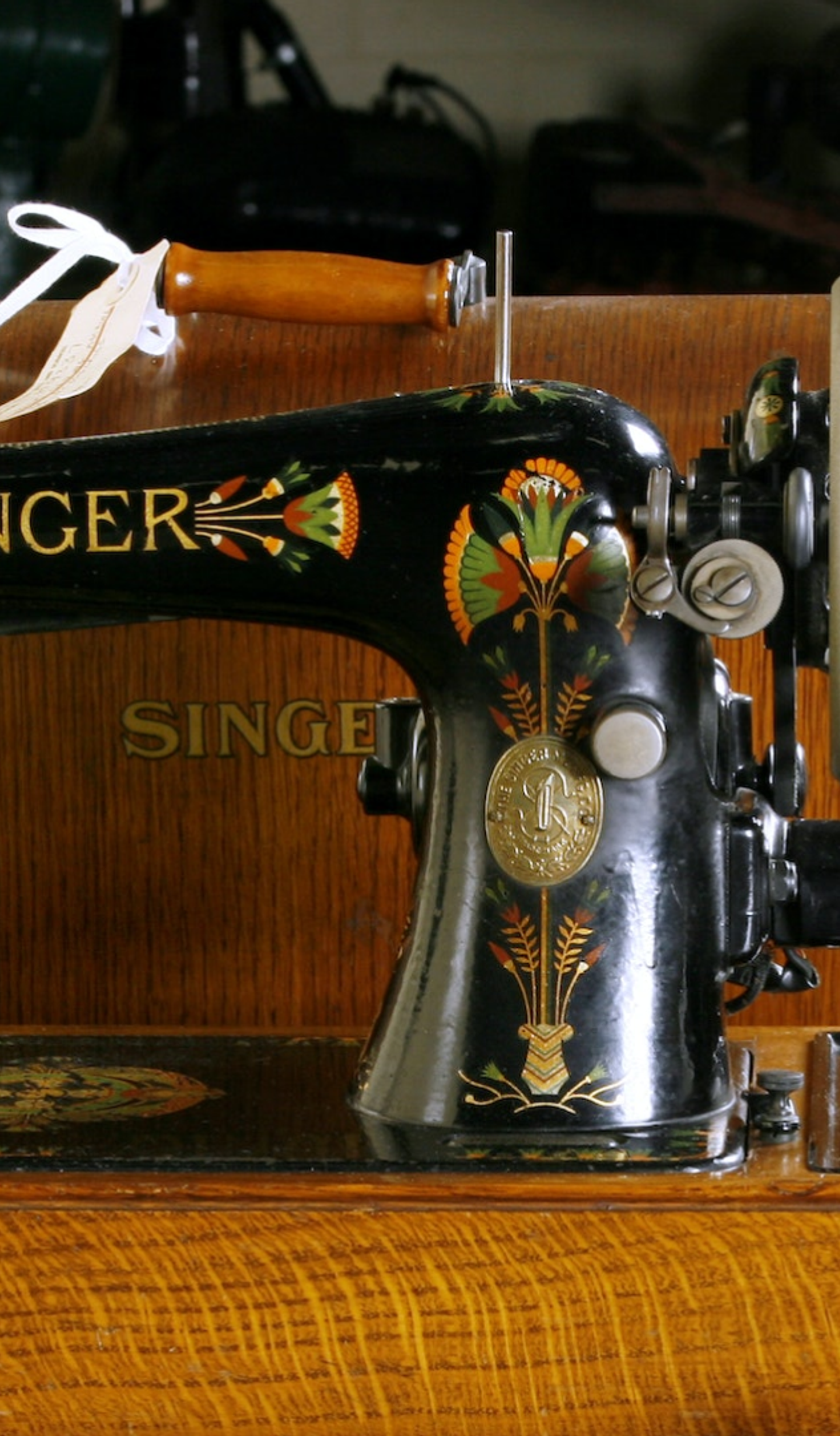 A black sewing machine with yellow, red and green flowers in a wooden box.