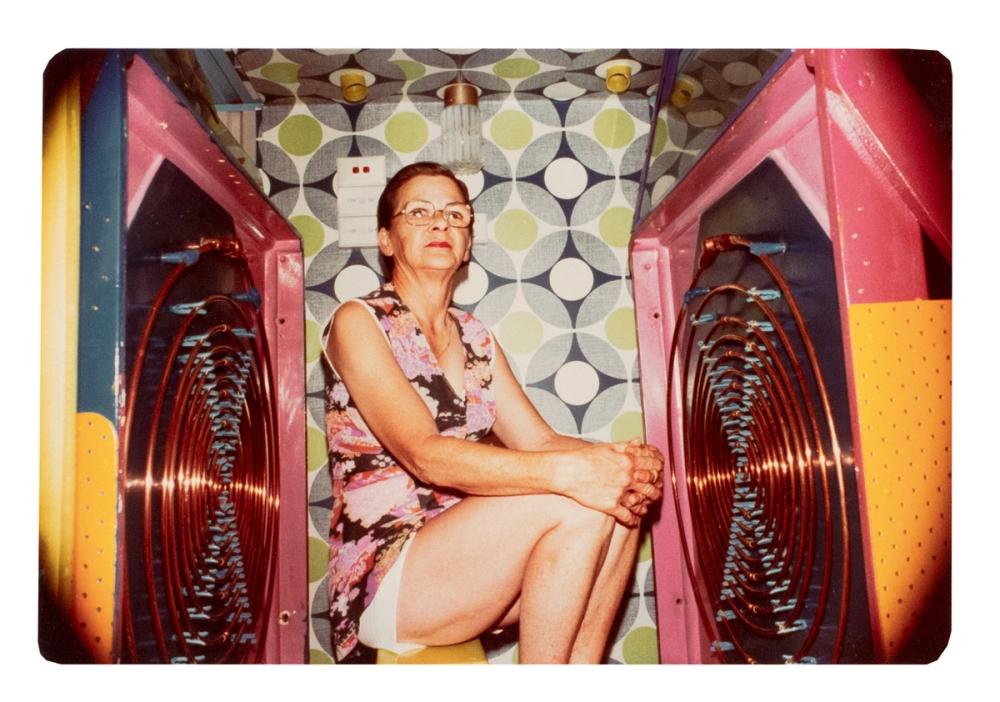 A lady in floral dress sitting in between two oscillator machines.