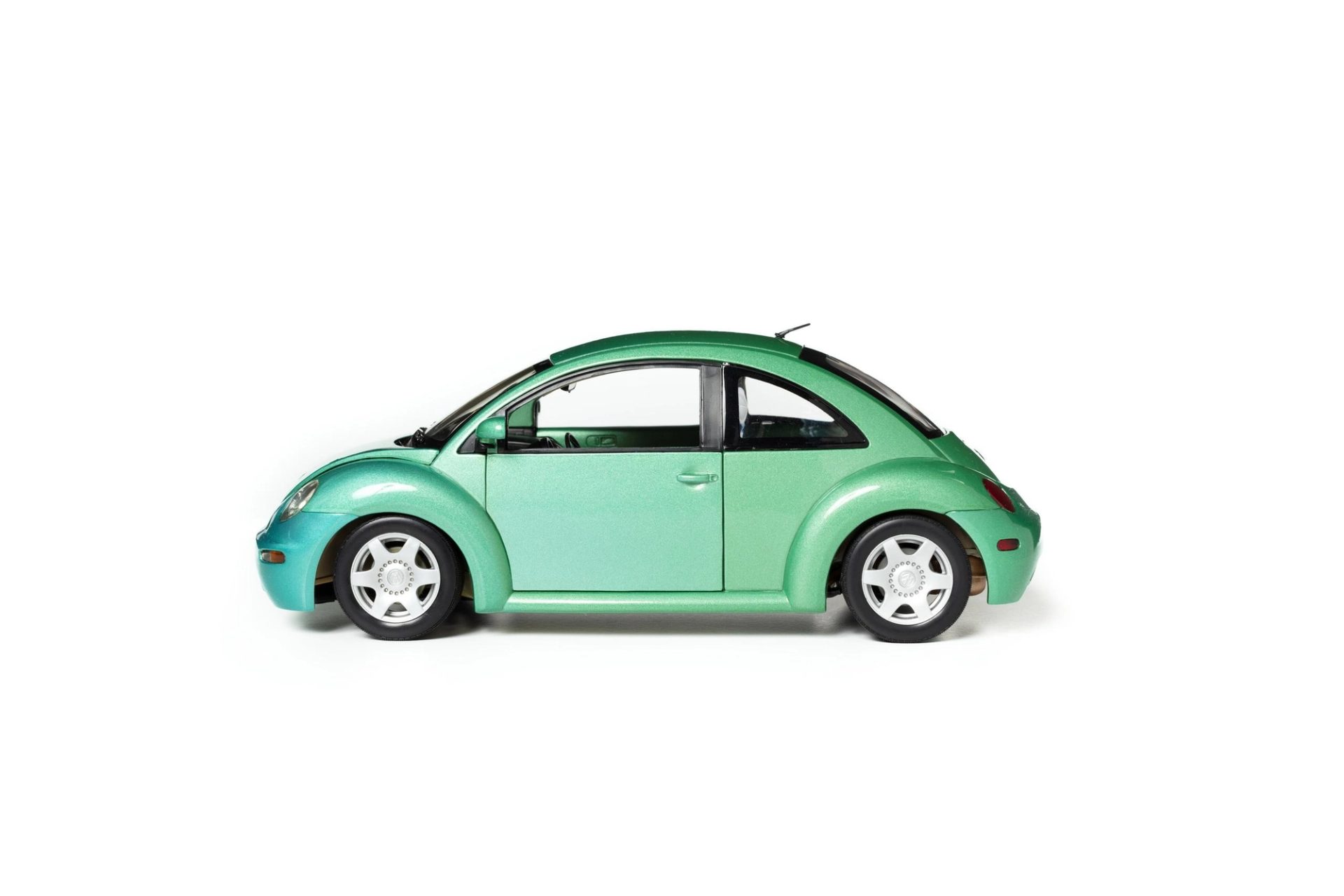 Side view of a toy VW Beetle car with metallic blue-green body and silver coloured hub caps
