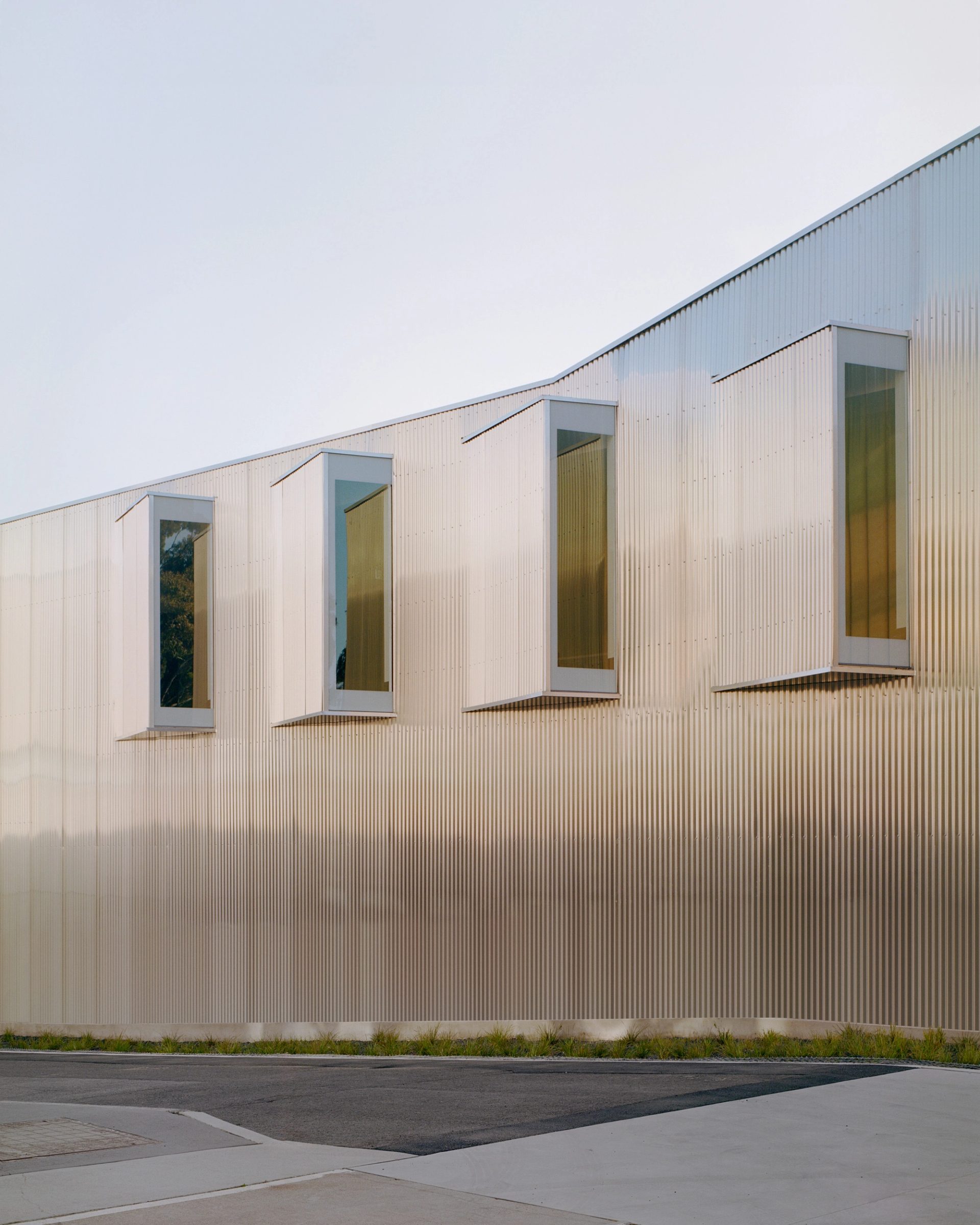 A row of four windows set at a 45 degree angle in the metal clad wall of a building.