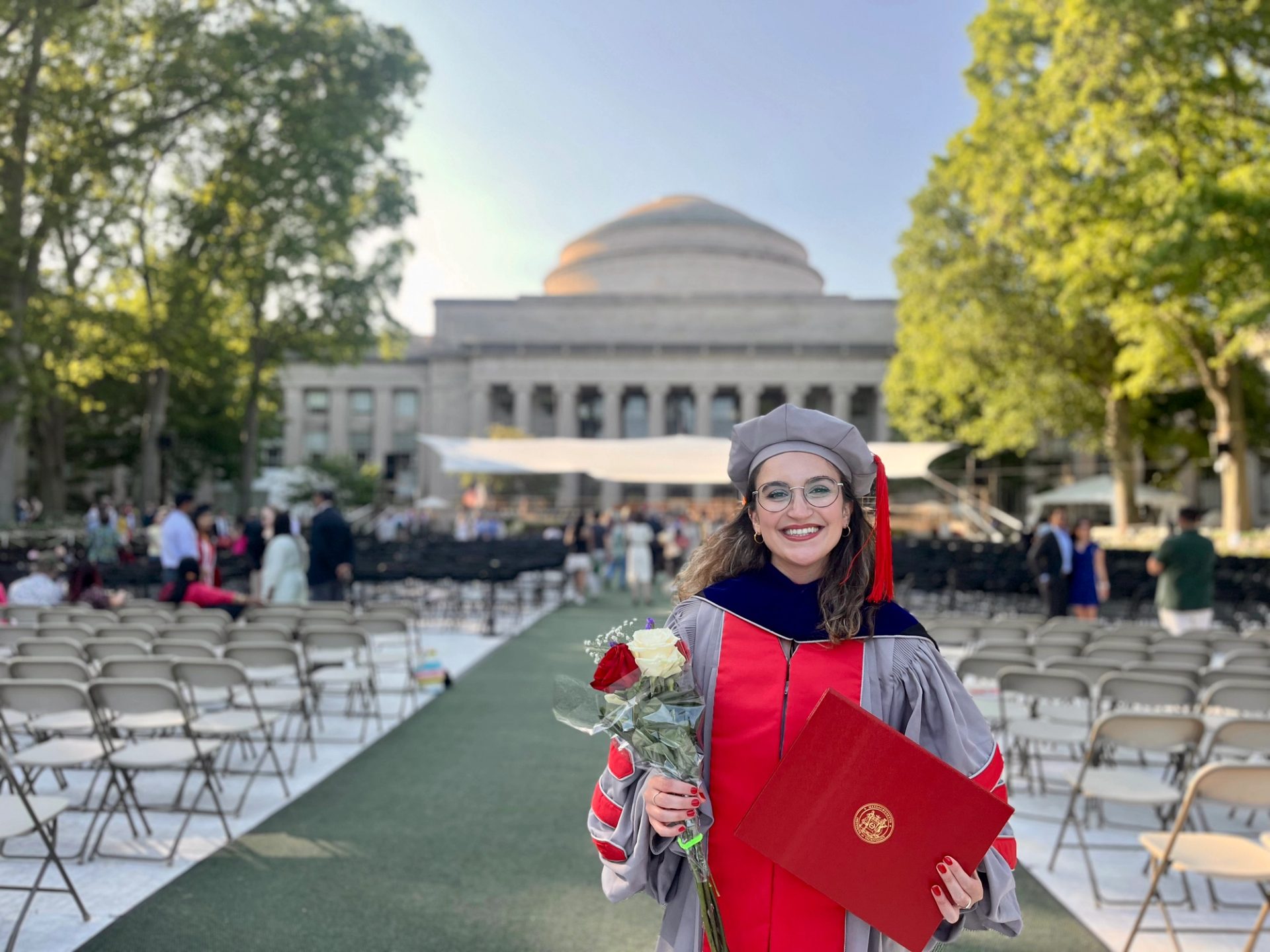 Graduate with flowers and paperwork amongst the ceremony isle.
