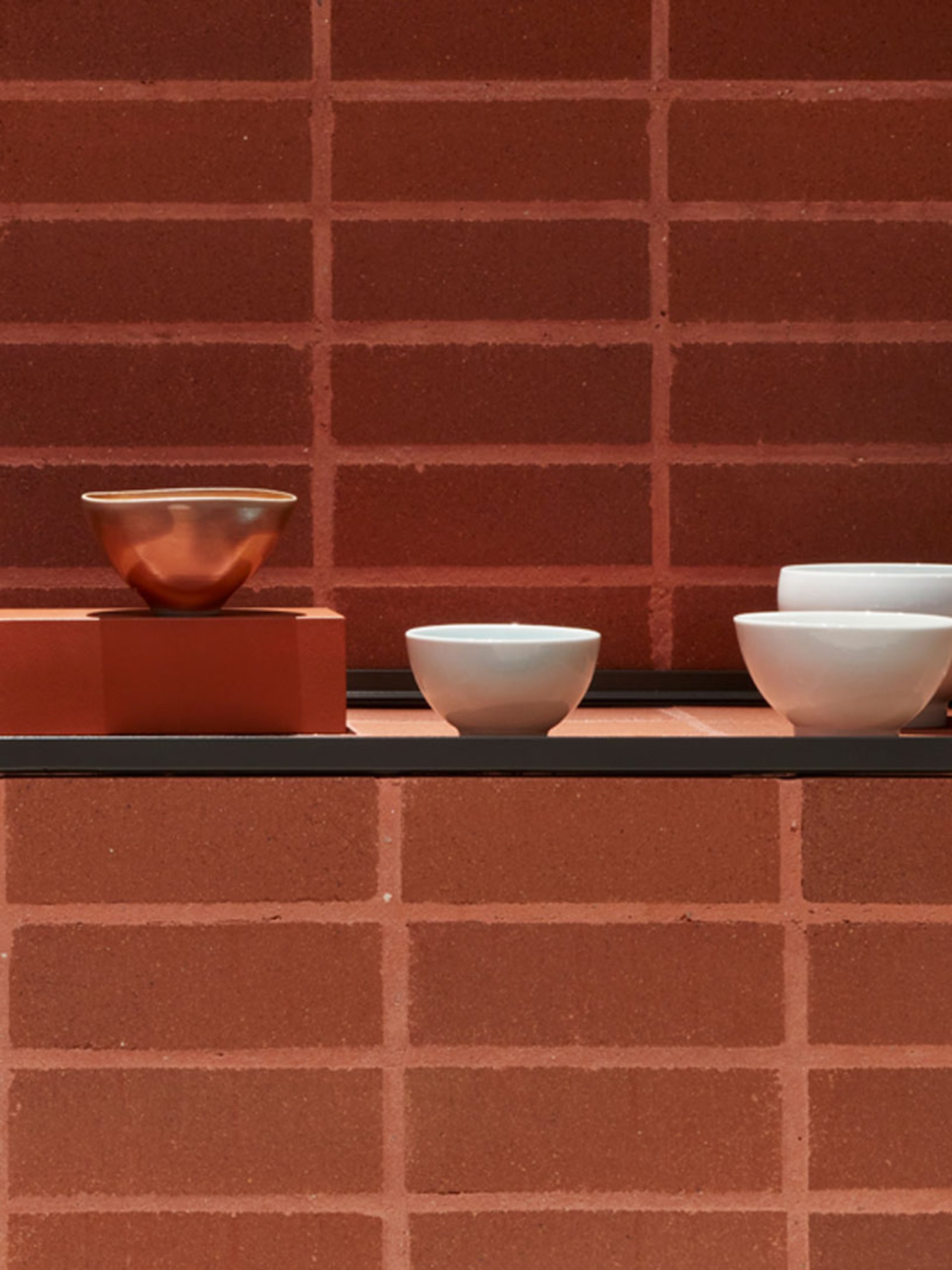 Ceramic bowls displayed on brick plinth.