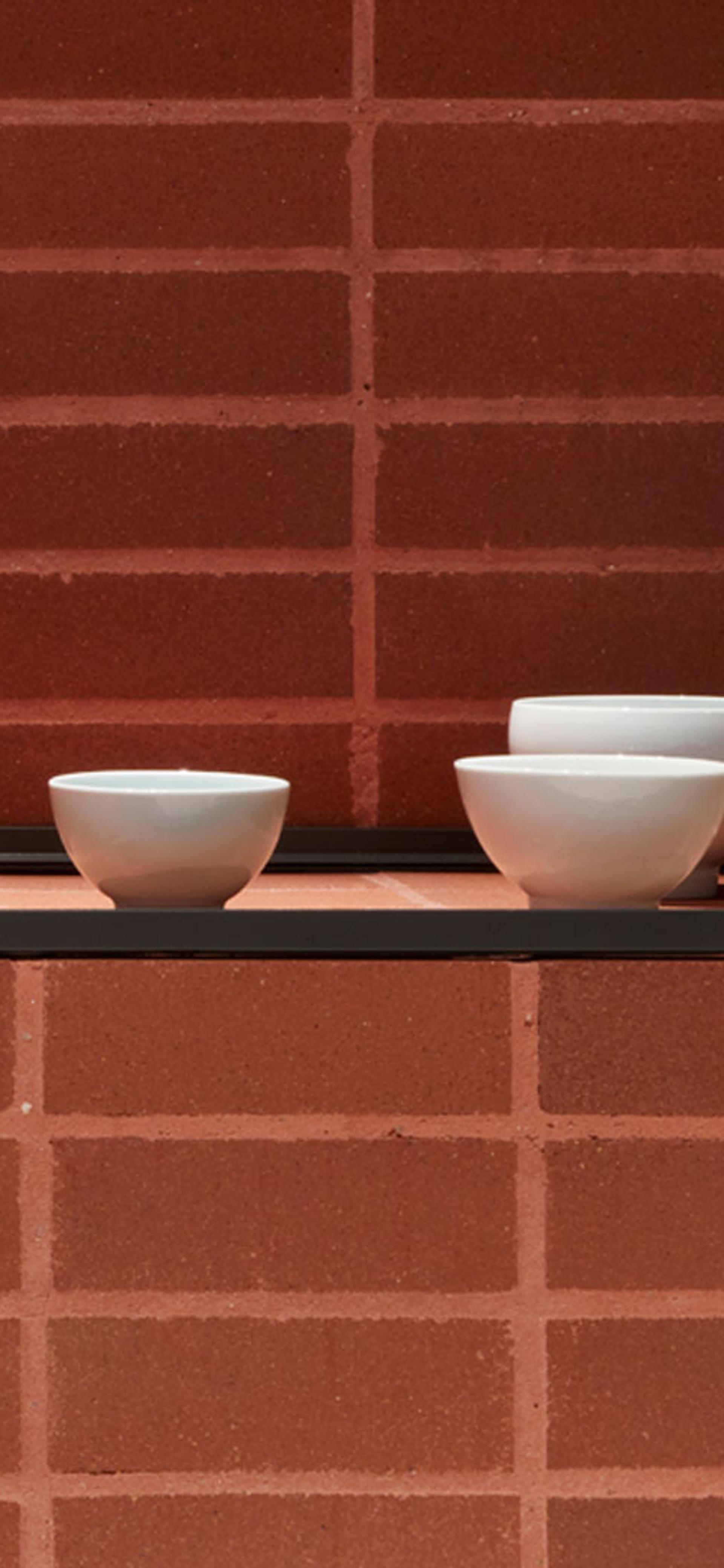 Ceramic bowls displayed on brick plinth.