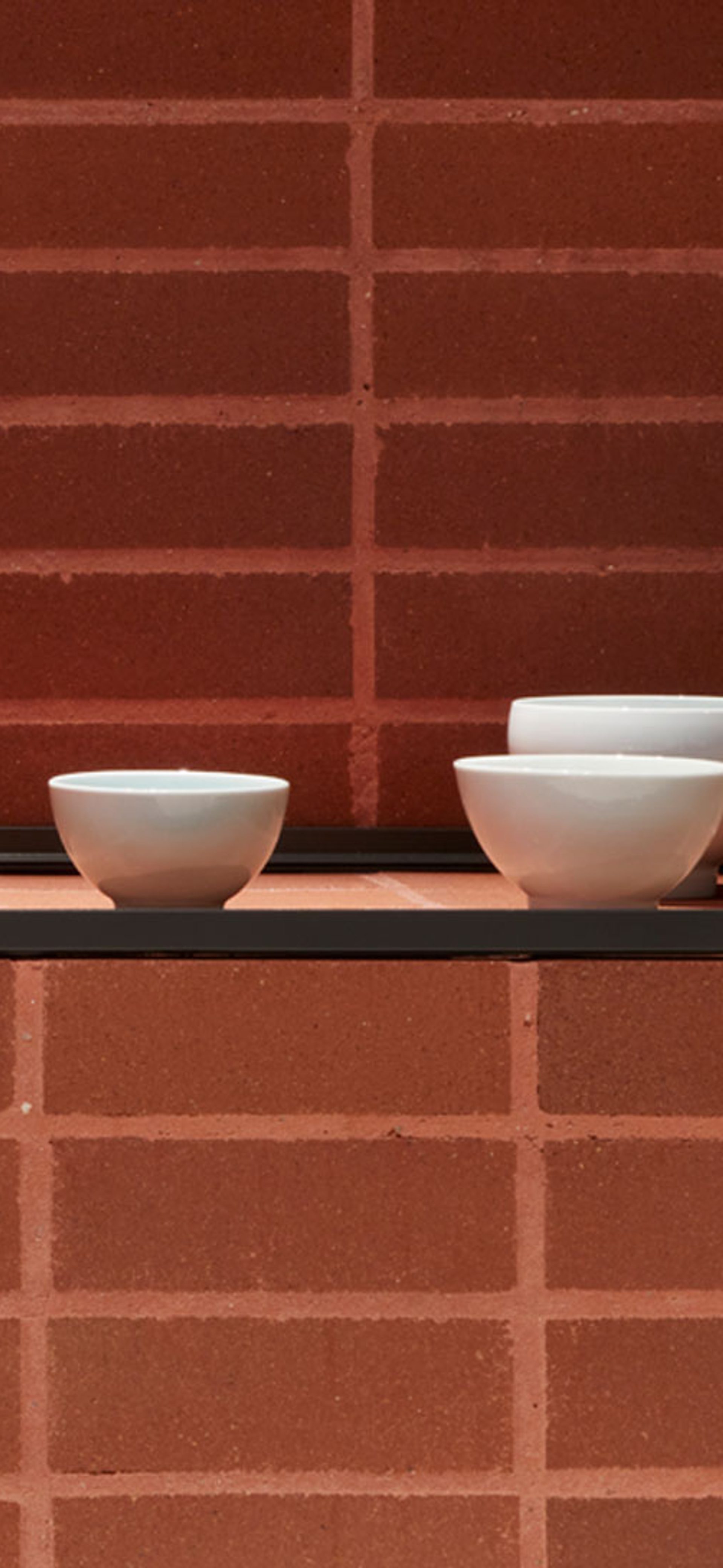 Ceramic bowls displayed on brick plinth.