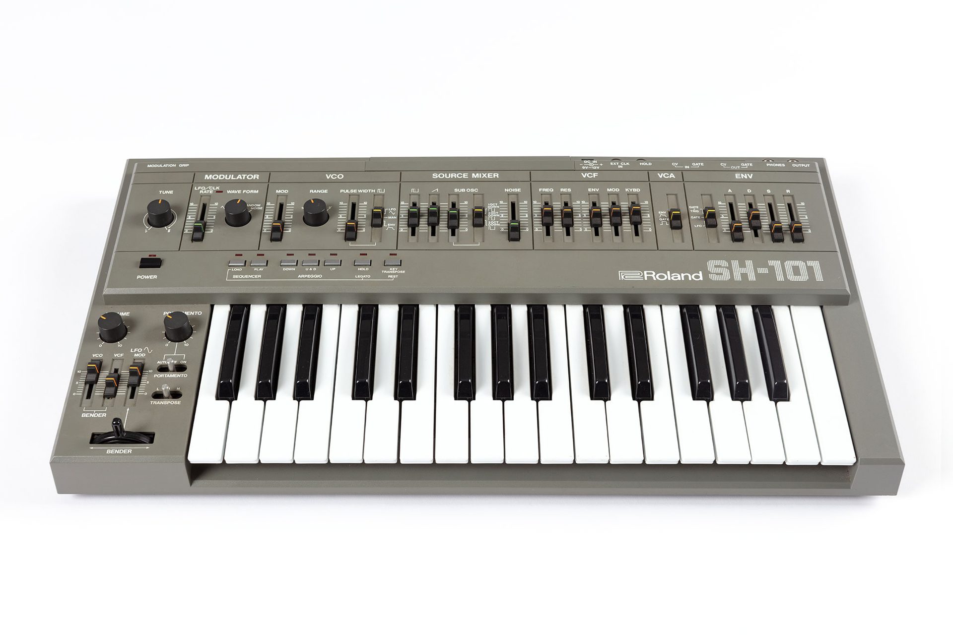 A grey synthesiser with multiple dials and sliders. It has a keyboard that spans two and a half octaves from f to c.