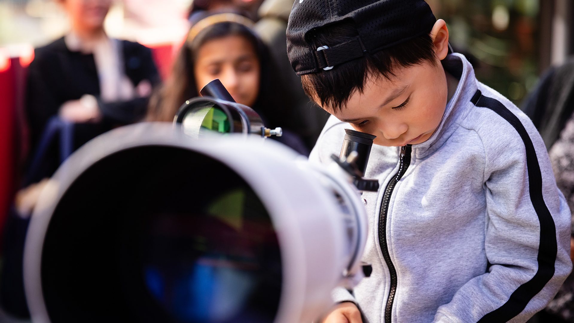 Little boy looks through telescope.
