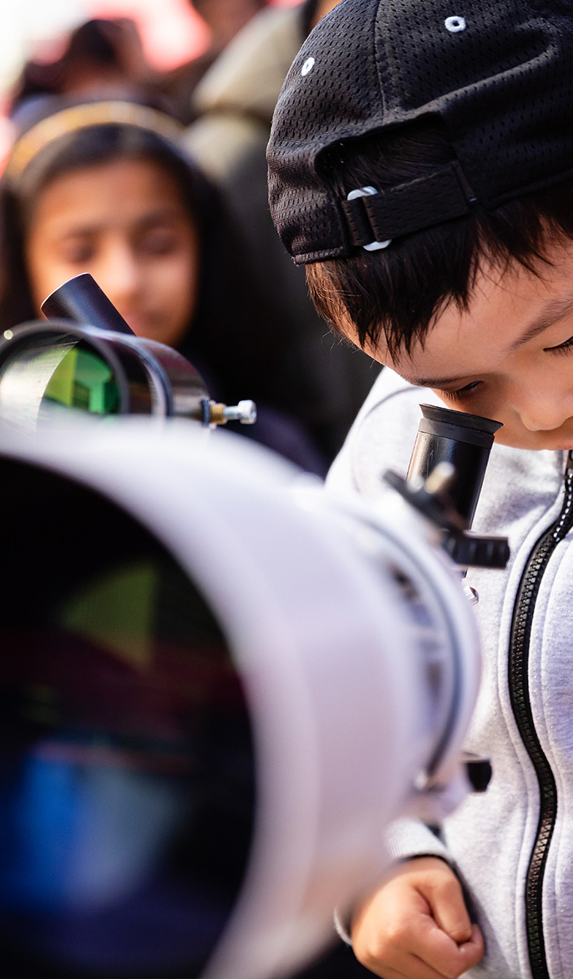Little boy looks through telescope.