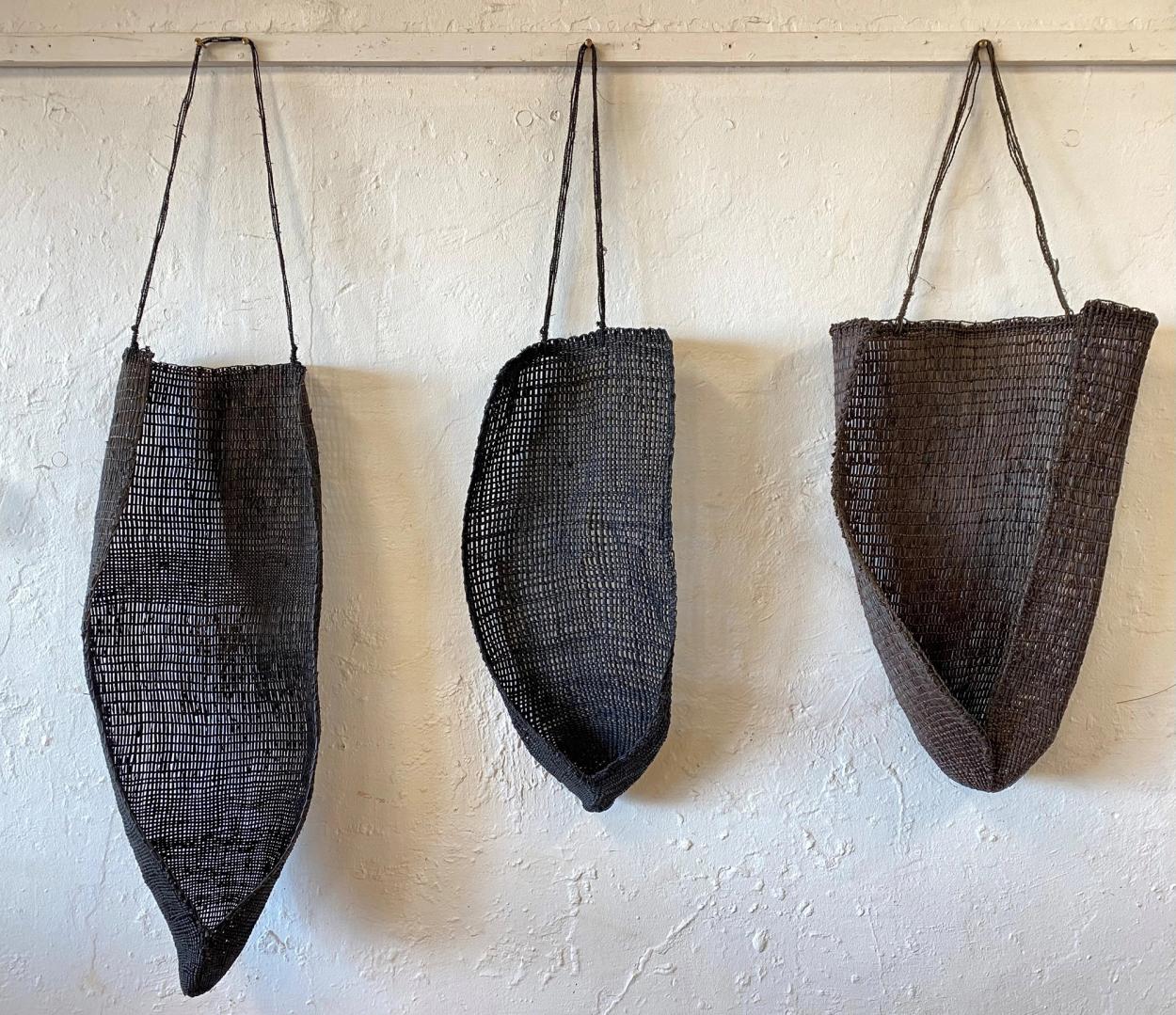 Three black woven artworks hanging in a row.