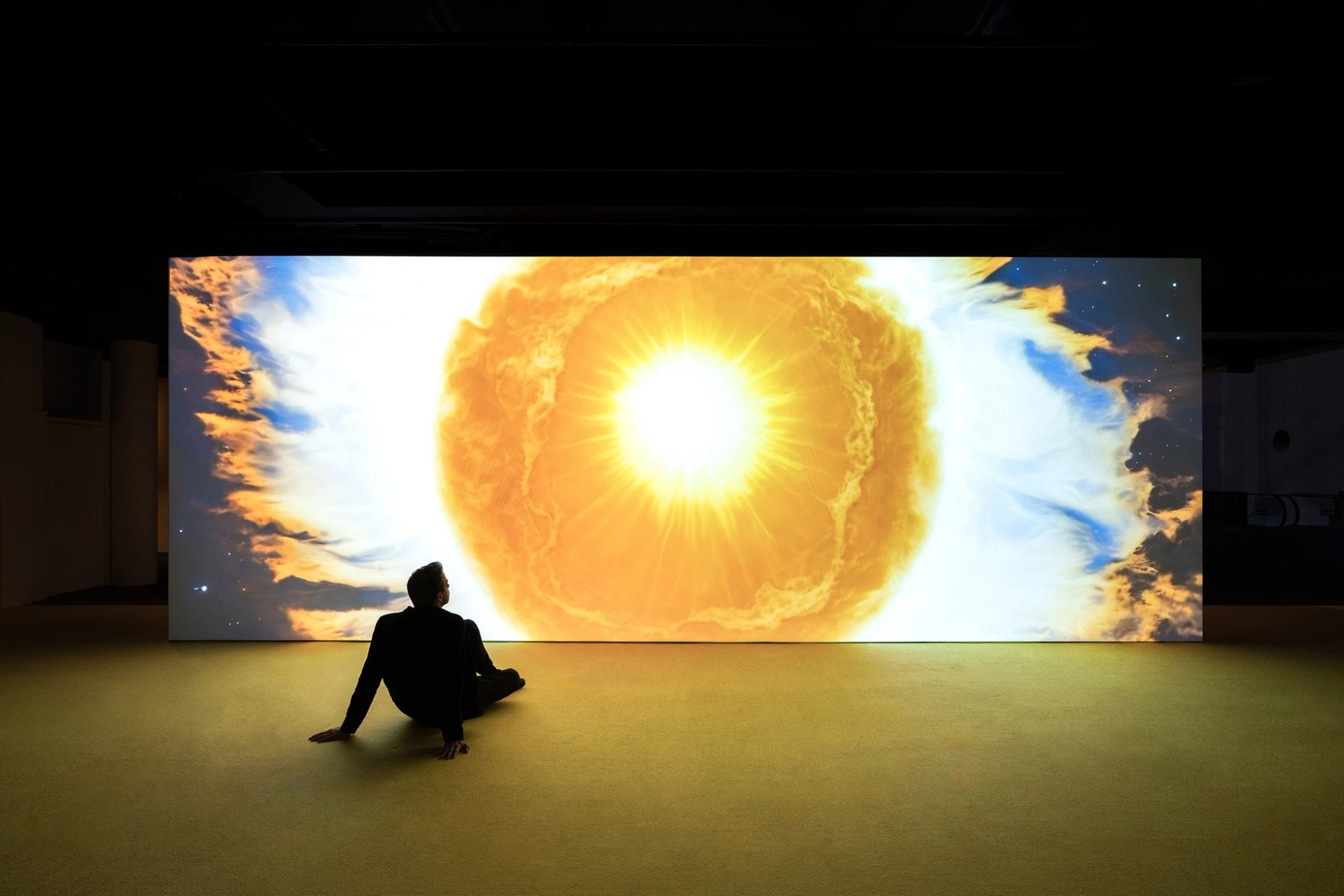 Man sits in front of projection of sun drawing