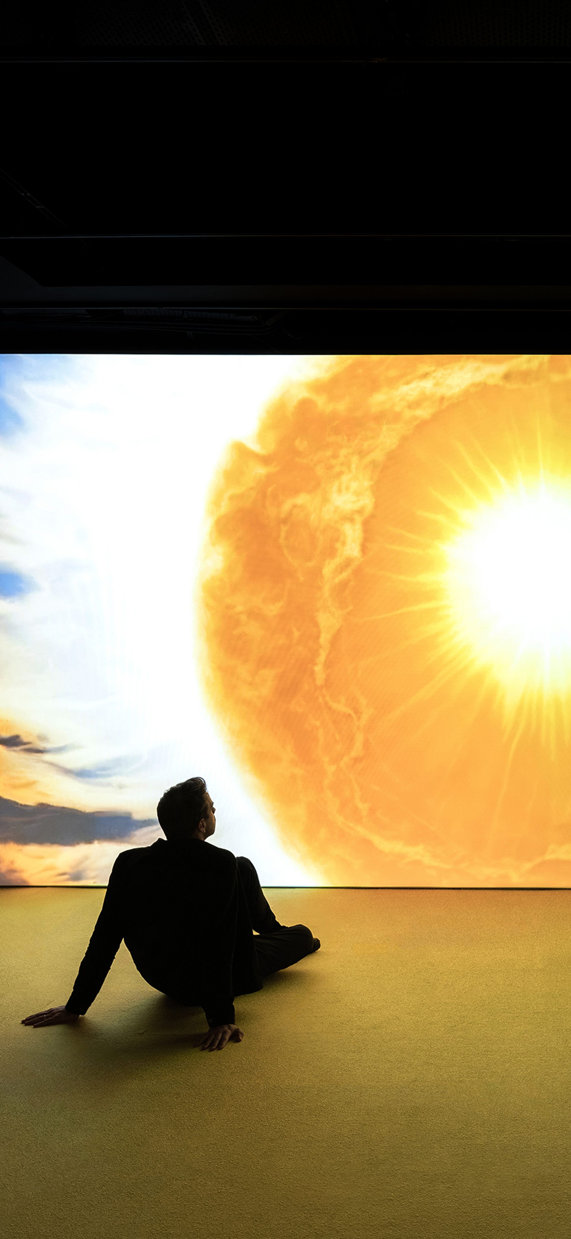Man sits in front of projection of sun drawing