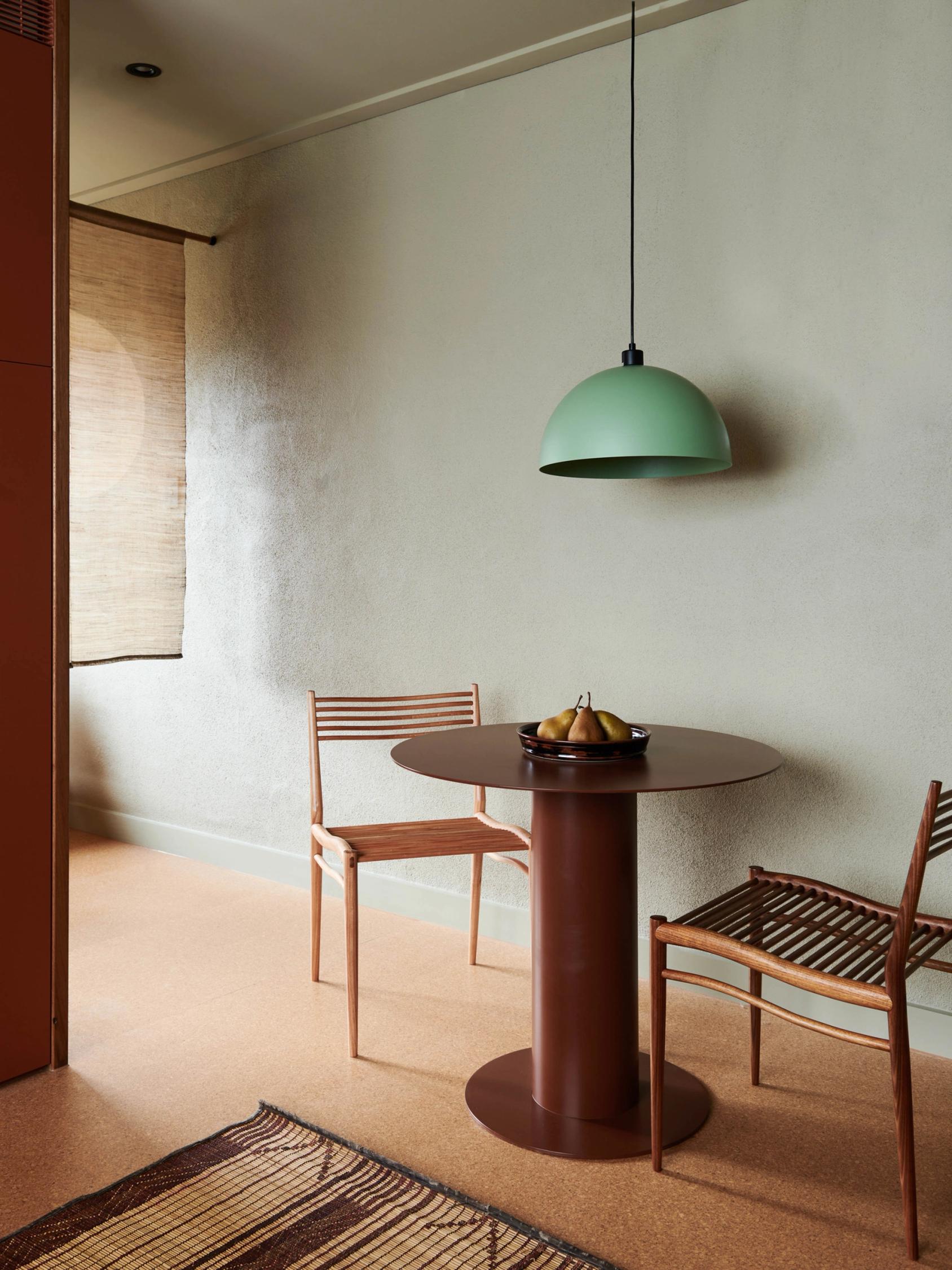 Dining chairs and circular table with lamp hanging from above.