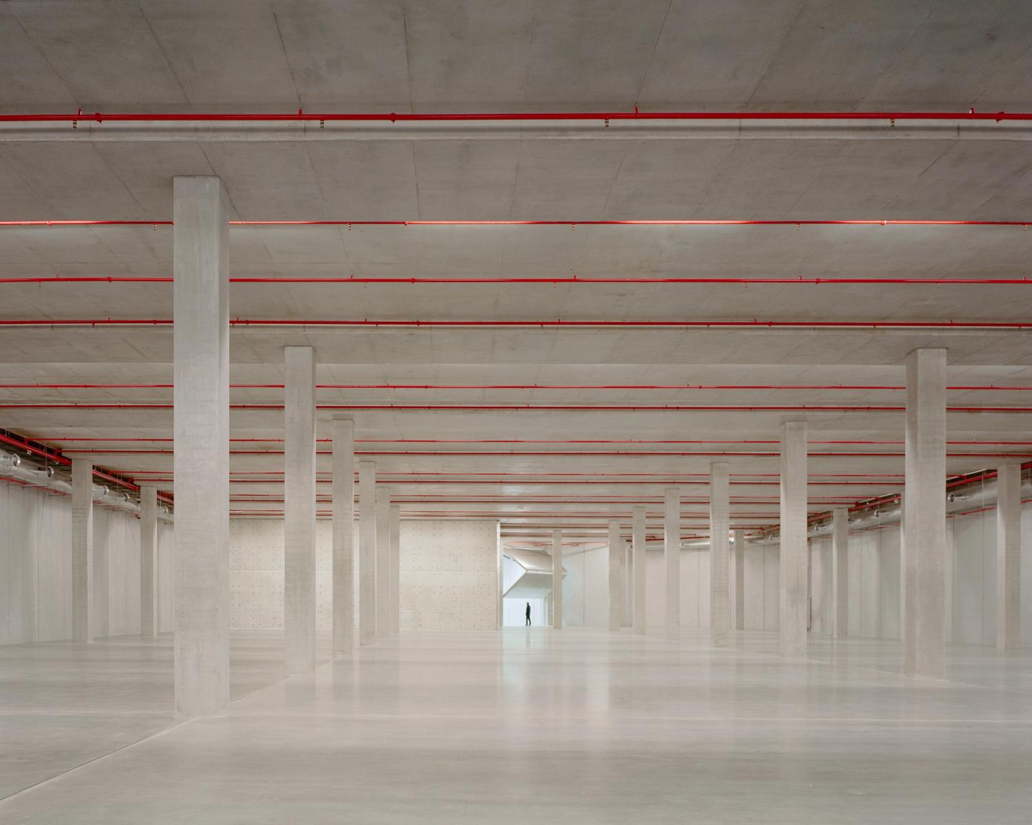 A huge concrete space with many columns. At the far end is a folding door.