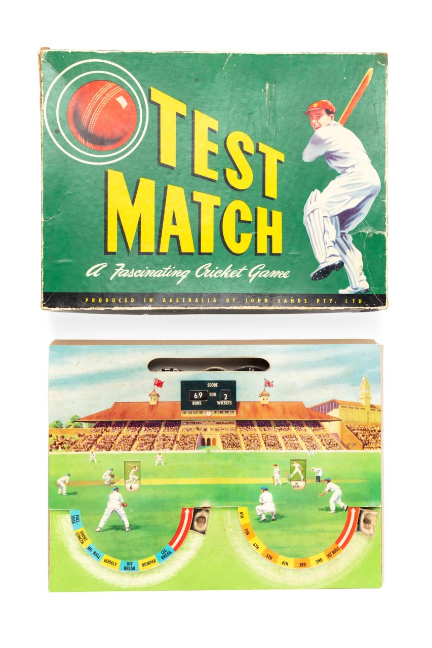 Board game consisting of a rectangular cardboard piece illustrated with a cricket ground, players and a scoreboard. Two semi-circles have been cut away from the background and are used to control the progress of the game. The packaging is a green cardboard box with lid, lid has an image of a batsman and a red cricket ball, containing 'a fascinating cricket game' called 'Test Match'.