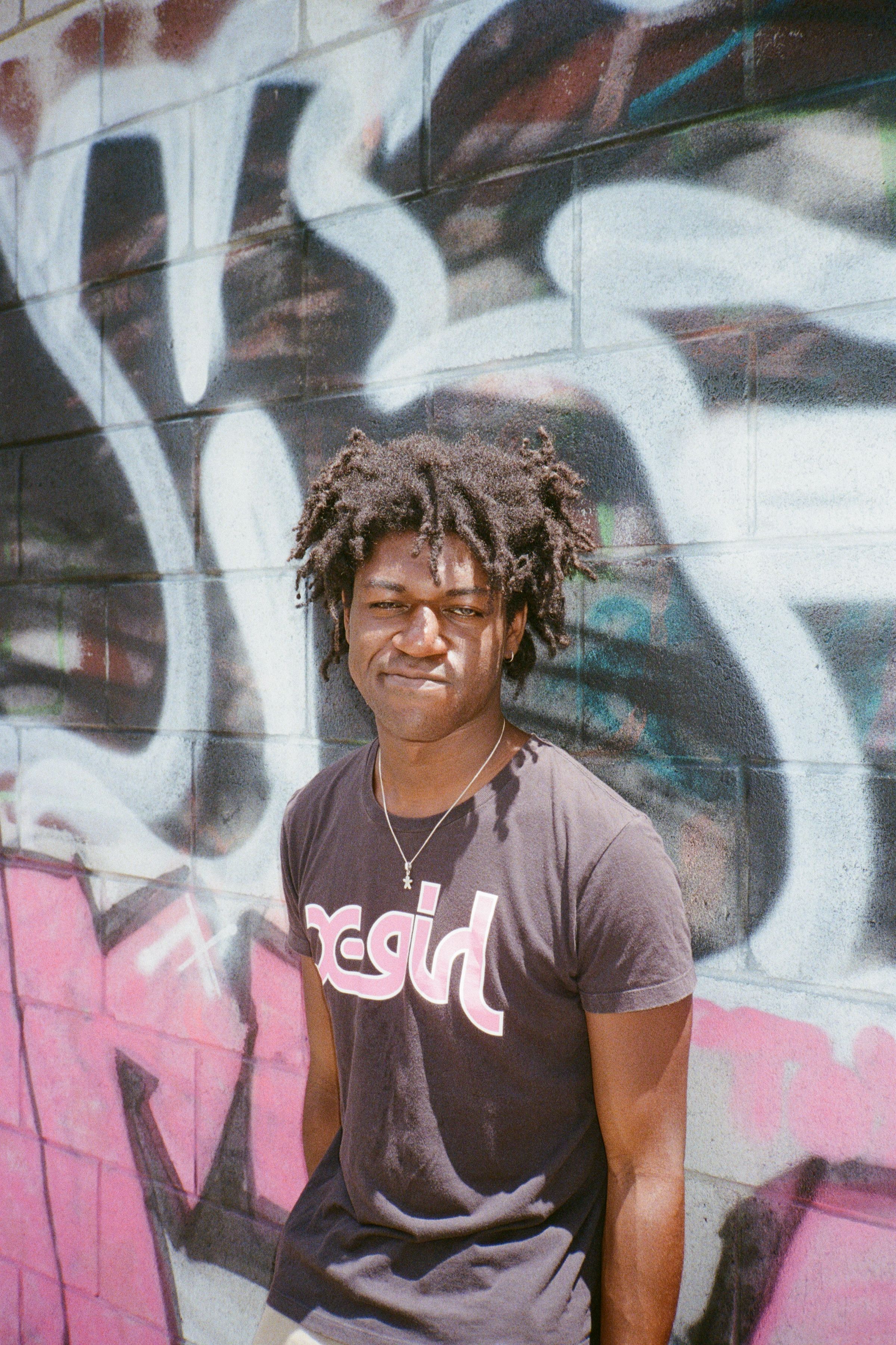 The musician Friday*, standing beside a wall, photographed by Christine Yau