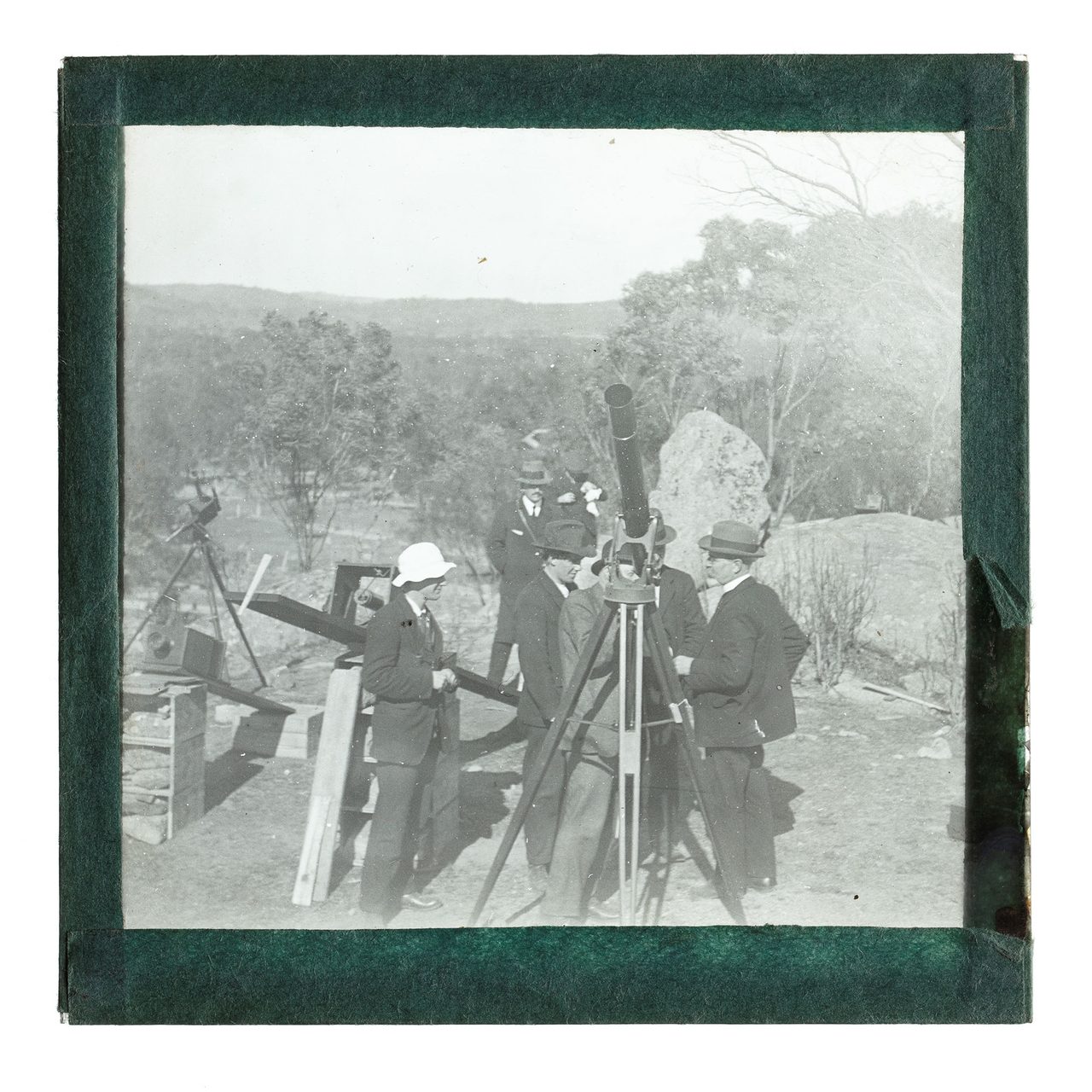 A black and white image of a group of men looking through a telescope.