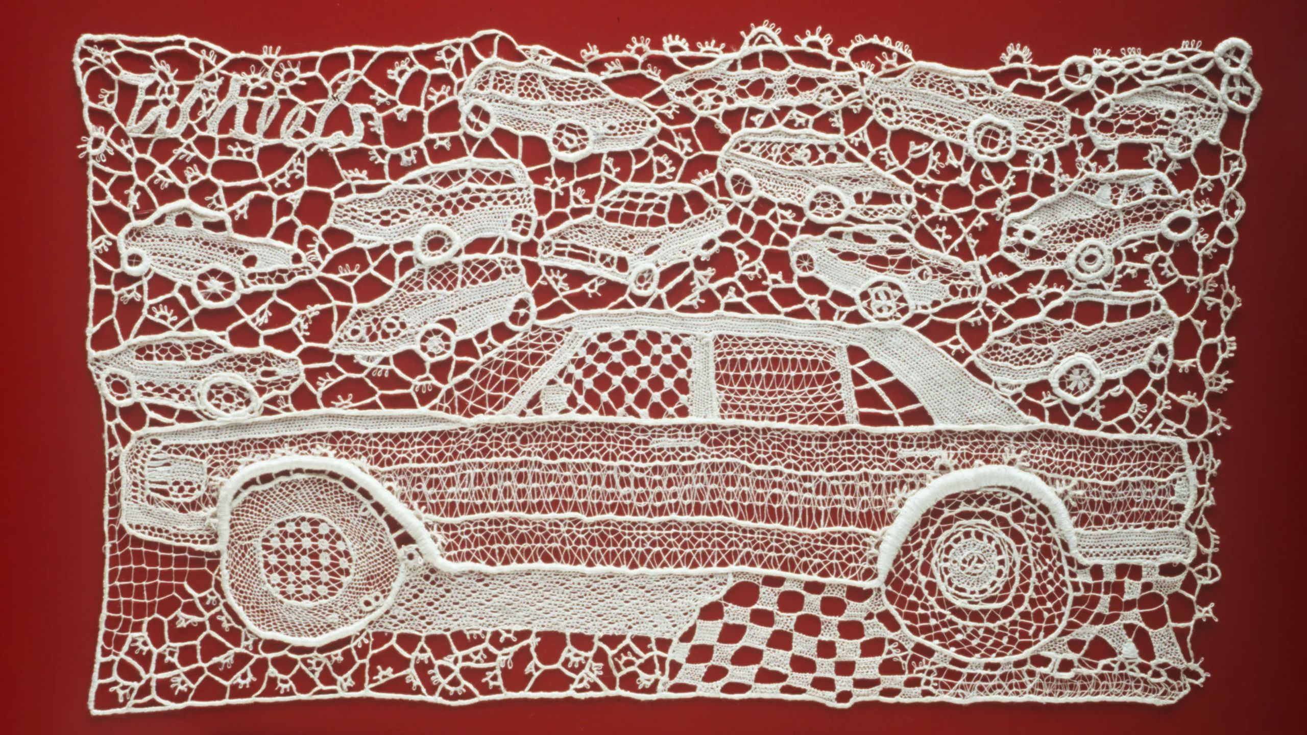 Rectangular lace panel, in 120 ecru linen thread, depicting a profile of a large car in the foreground with a number of small cars in the 3/4 profile randomly scattered in the background. All worked in many different needle-lace stitch patterns. Mounted with nylon thread onto red painted sheet of metal referencing a car door.