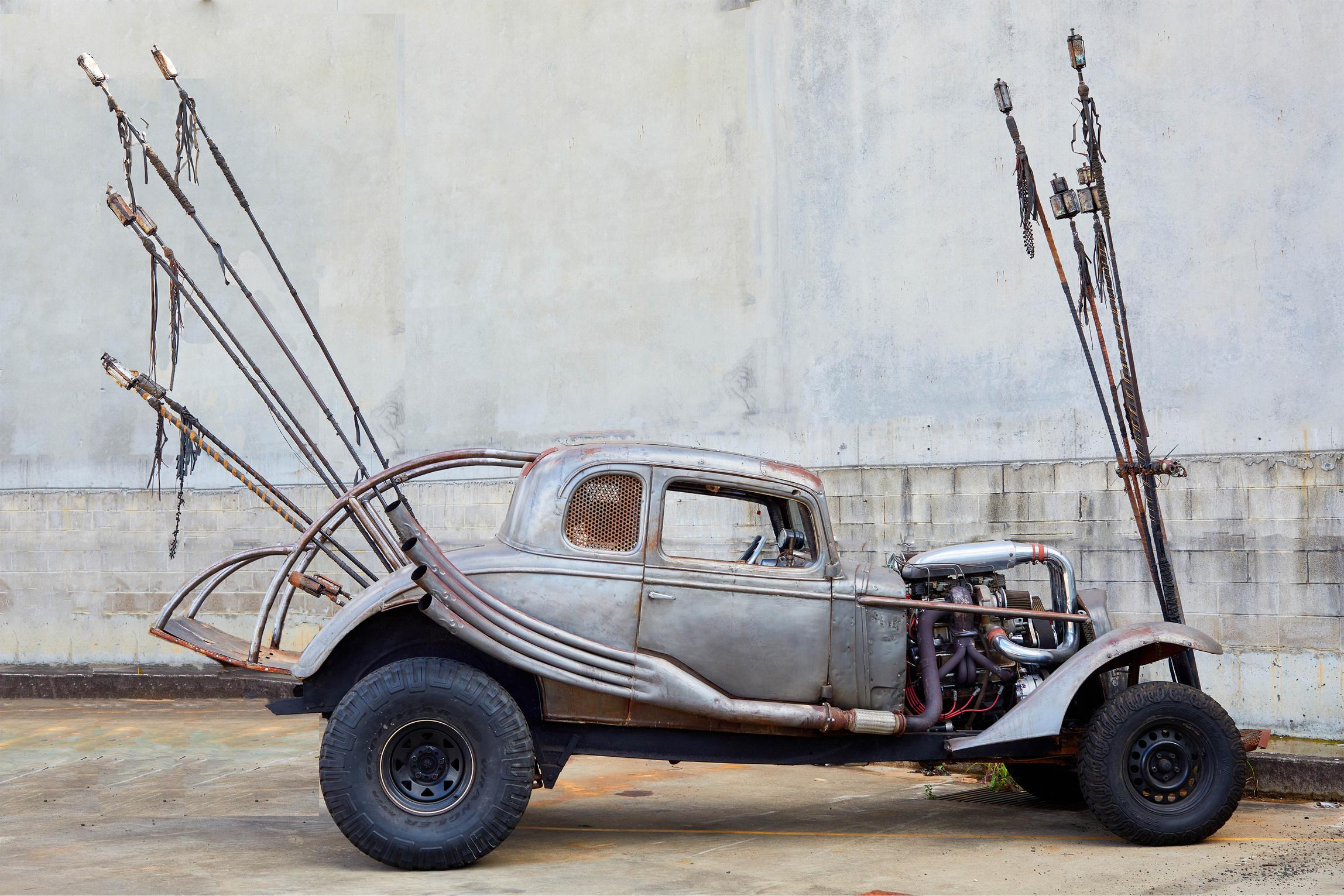 Old jag with long sticks sticking from the front bonnet and rear of car.