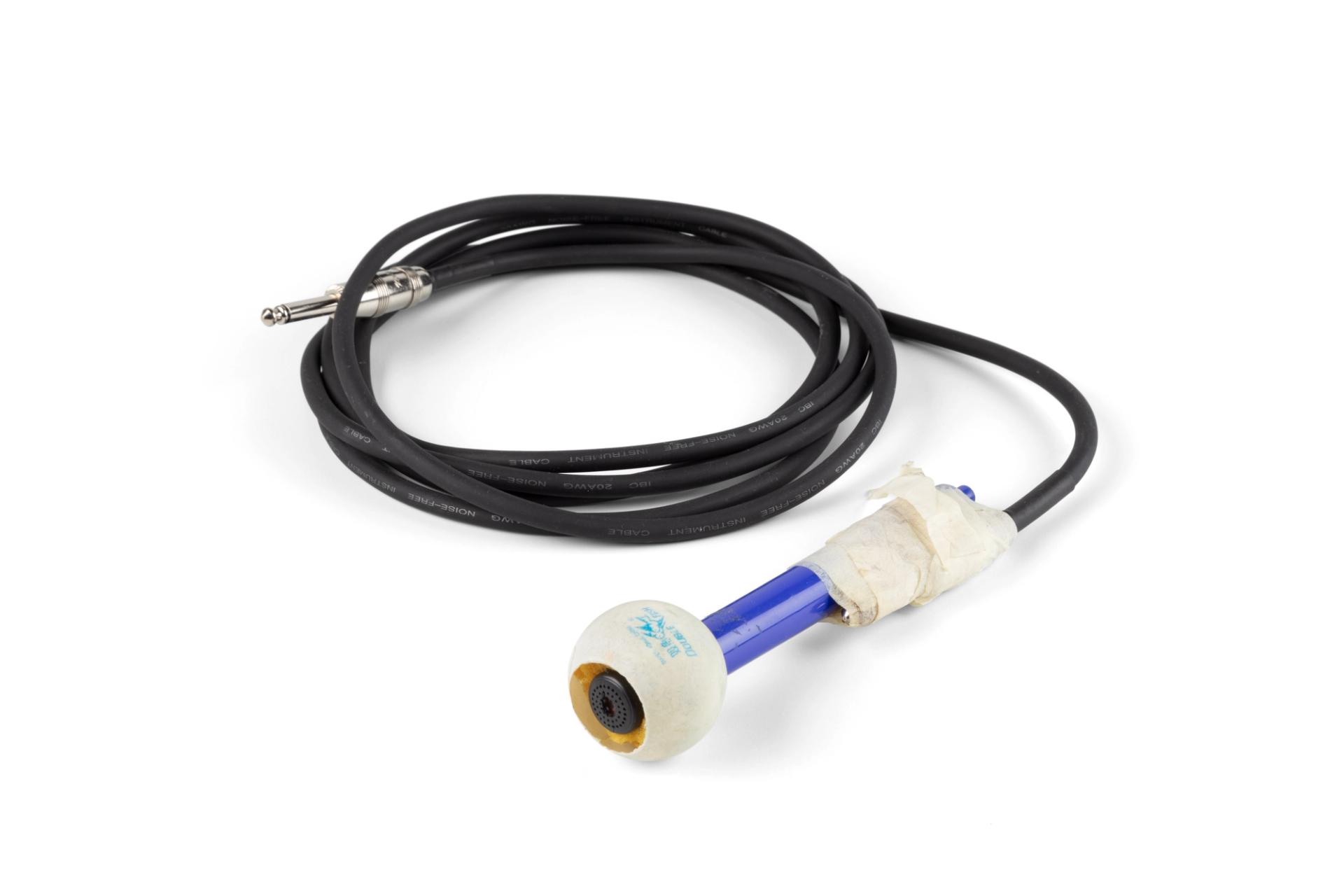 The microphone is made from a headphone ear-bud acting as the magnet, coil and diaphragm, a ping-pong ball with section of the the top removed, foam around the ear-bud, an empty felt-tip pen and a guitar lead.