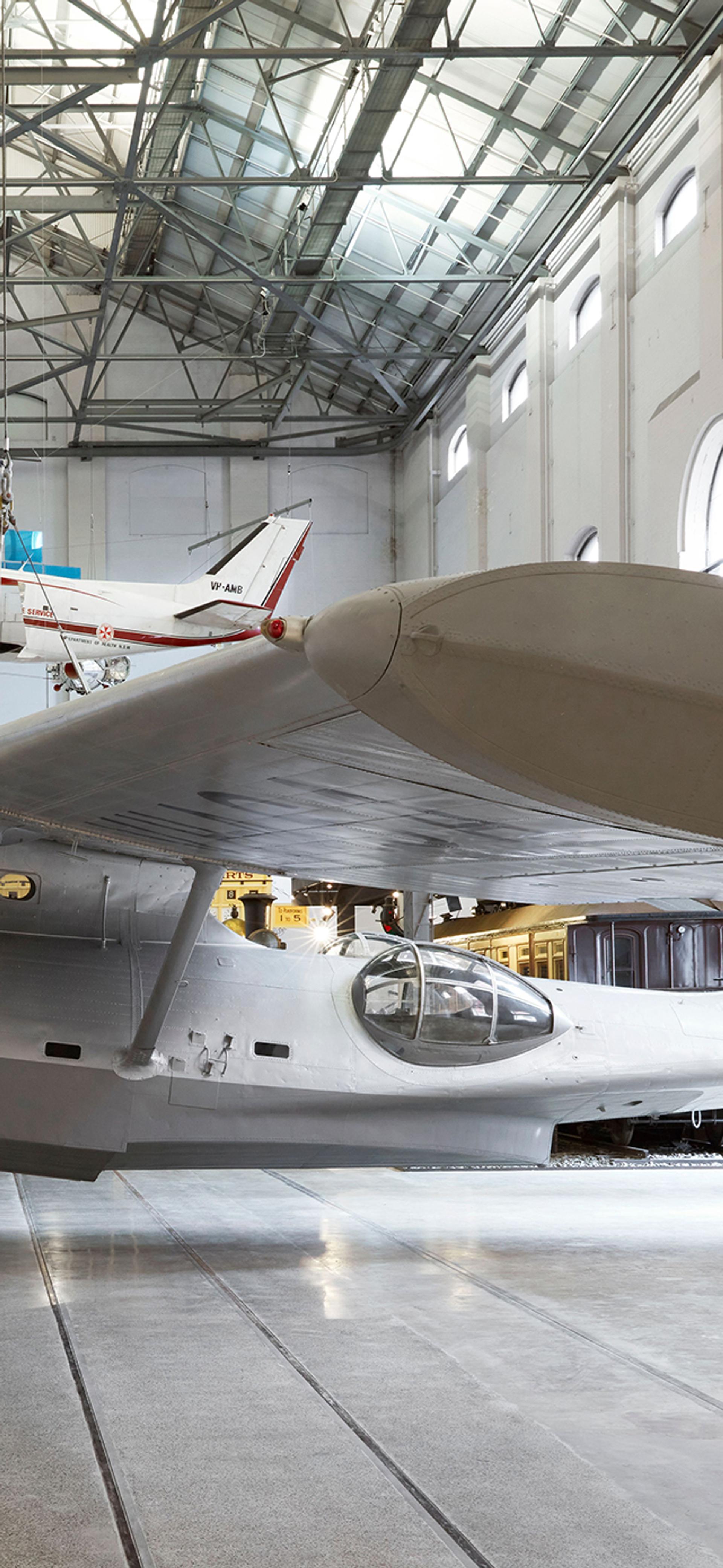 Silver plane exhibited in a large gallery space.