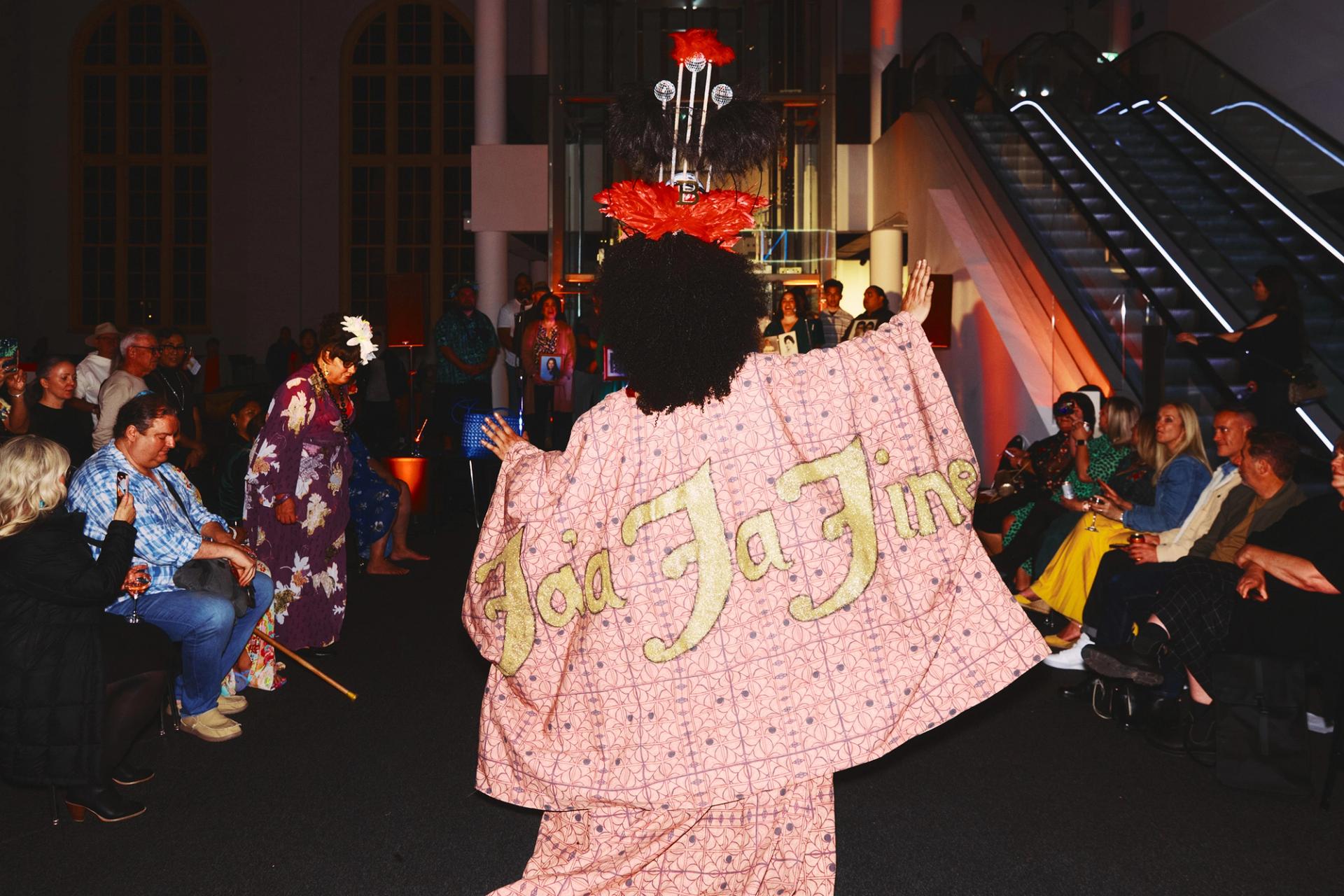 A drag queen, mid performance, with her back to the camera.