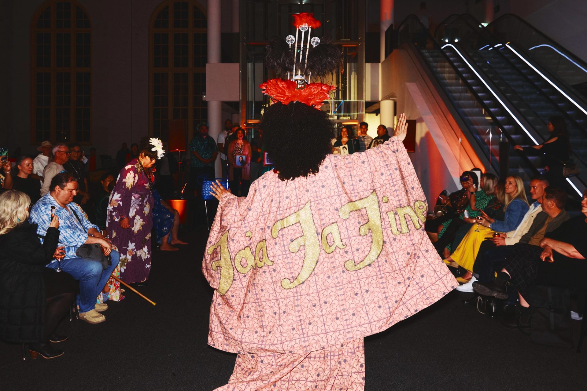 A drag queen, mid performance, with her back to the camera.