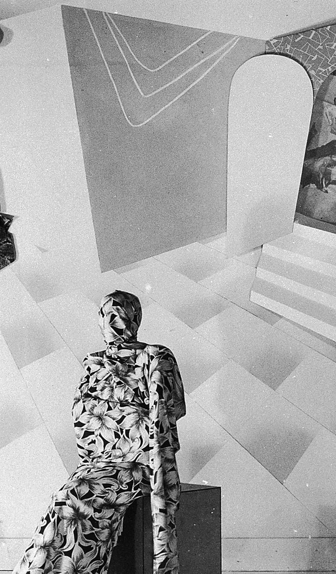 Black and white photograph of theatrical fund raising event, dancer sits on a box on stage, swathed from head to toe in a screenprinted floral Prestige fabric, the collage backdrop shows surrealistic set made of prints and paper, art director Gerard Herbst, Melbourne, Victoria, Australia, 1950–1955