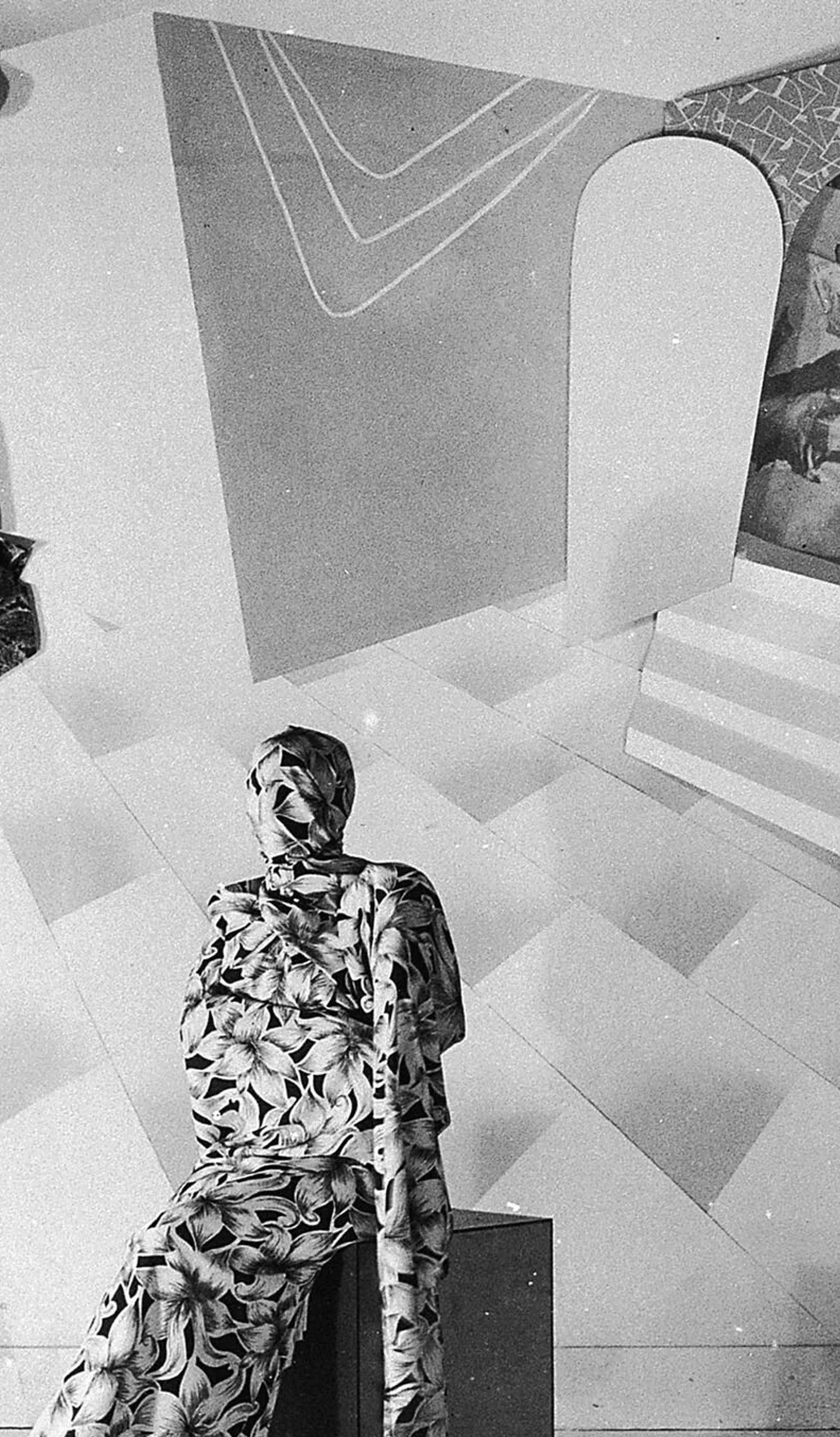 Black and white photograph of theatrical fund raising event, dancer sits on a box on stage, swathed from head to toe in a screenprinted floral Prestige fabric, the collage backdrop shows surrealistic set made of prints and paper, art director Gerard Herbst, Melbourne, Victoria, Australia, 1950–1955